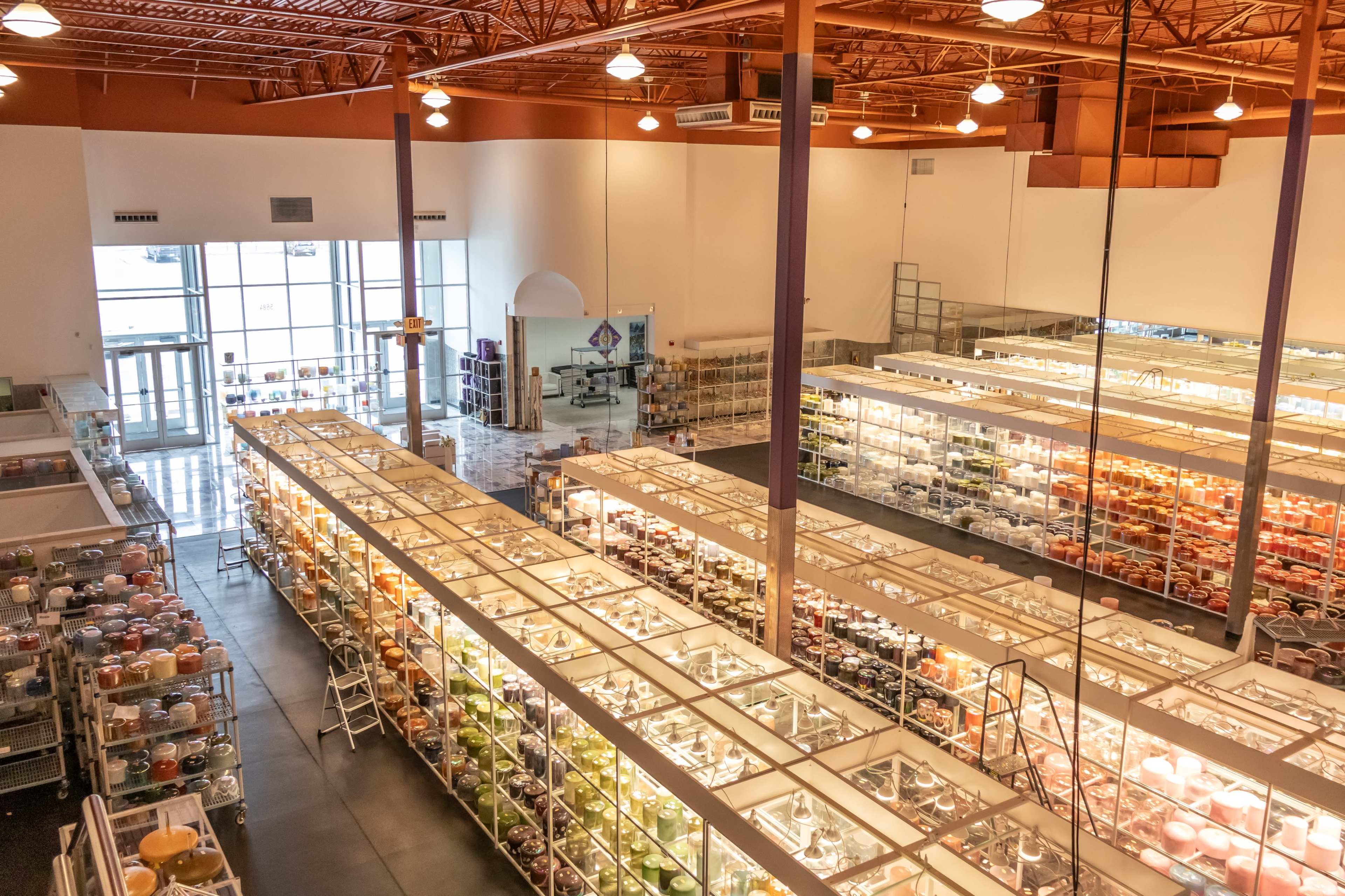 The image shows a spacious store with rows of clear display cases filled with various items, and large windows allowing natural light to fill the area.
