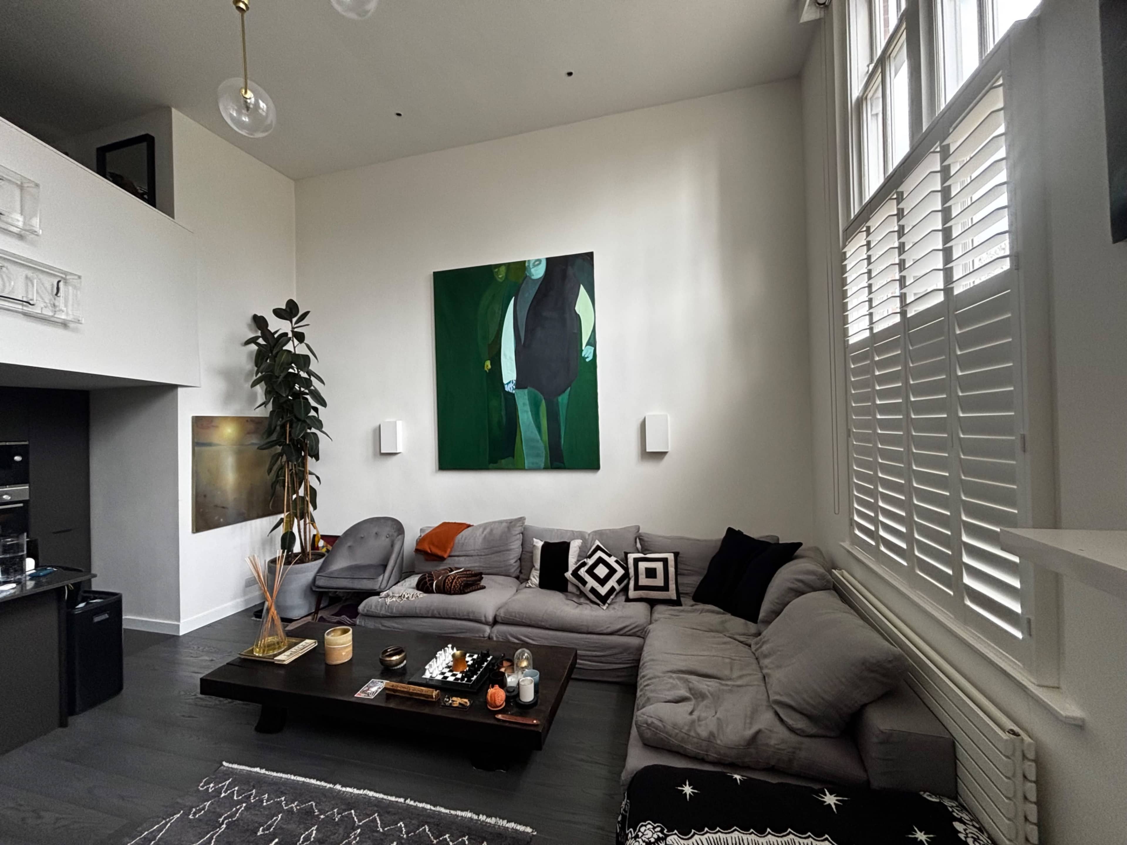 A modern living room features a large painting on the wall, a sectional gray couch, and a coffee table adorned with decorative items.