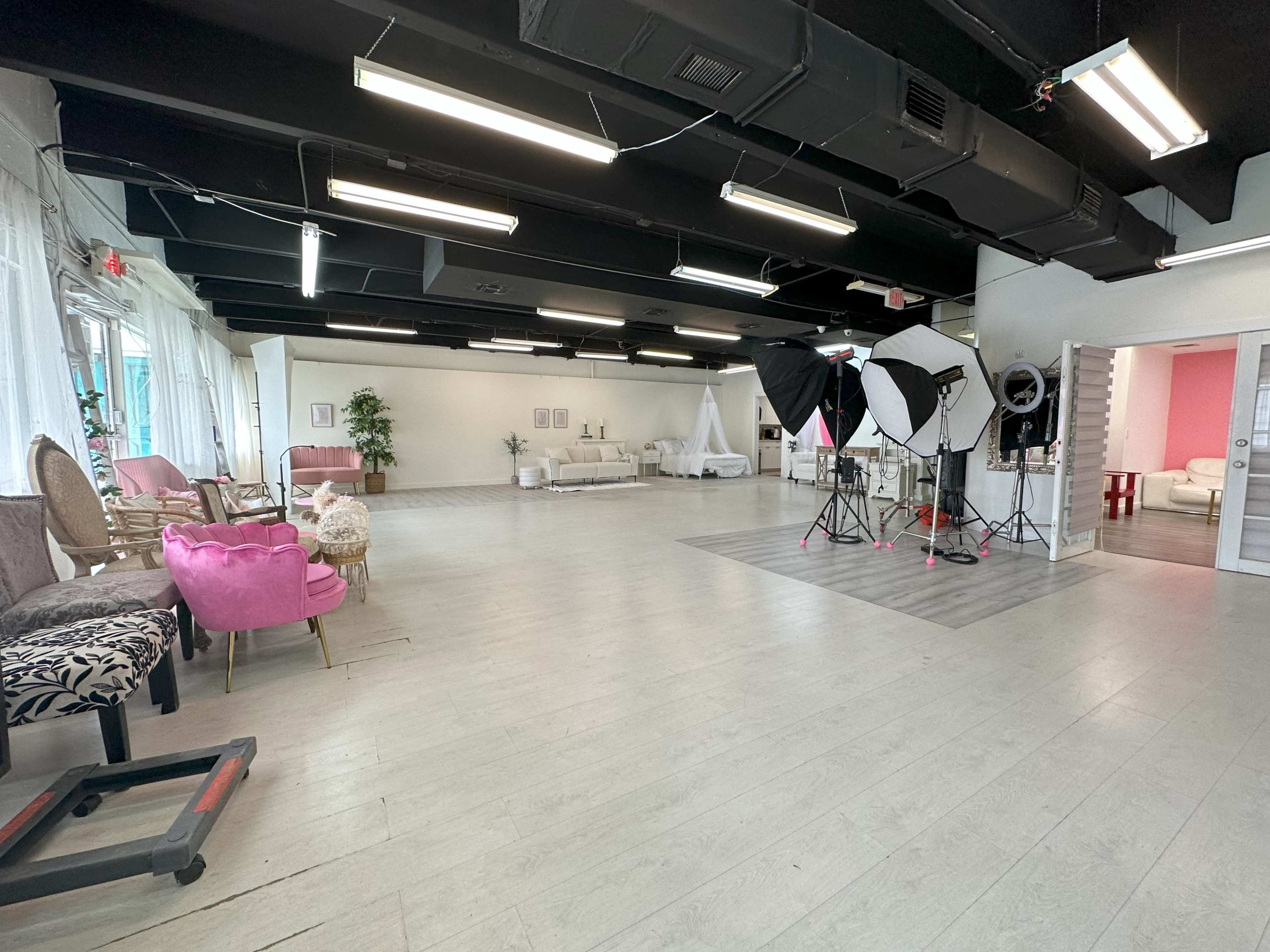 A spacious interior room designed for photography, featuring various seating arrangements and multiple lighting setups.