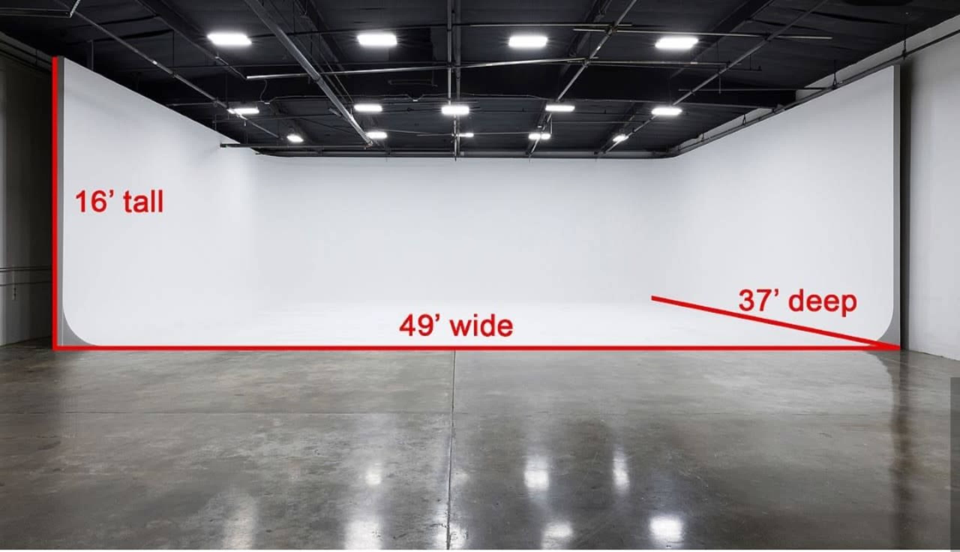 A large studio space with white walls, measuring 16 feet tall, 49 feet wide, and 37 feet deep, with a concrete floor.