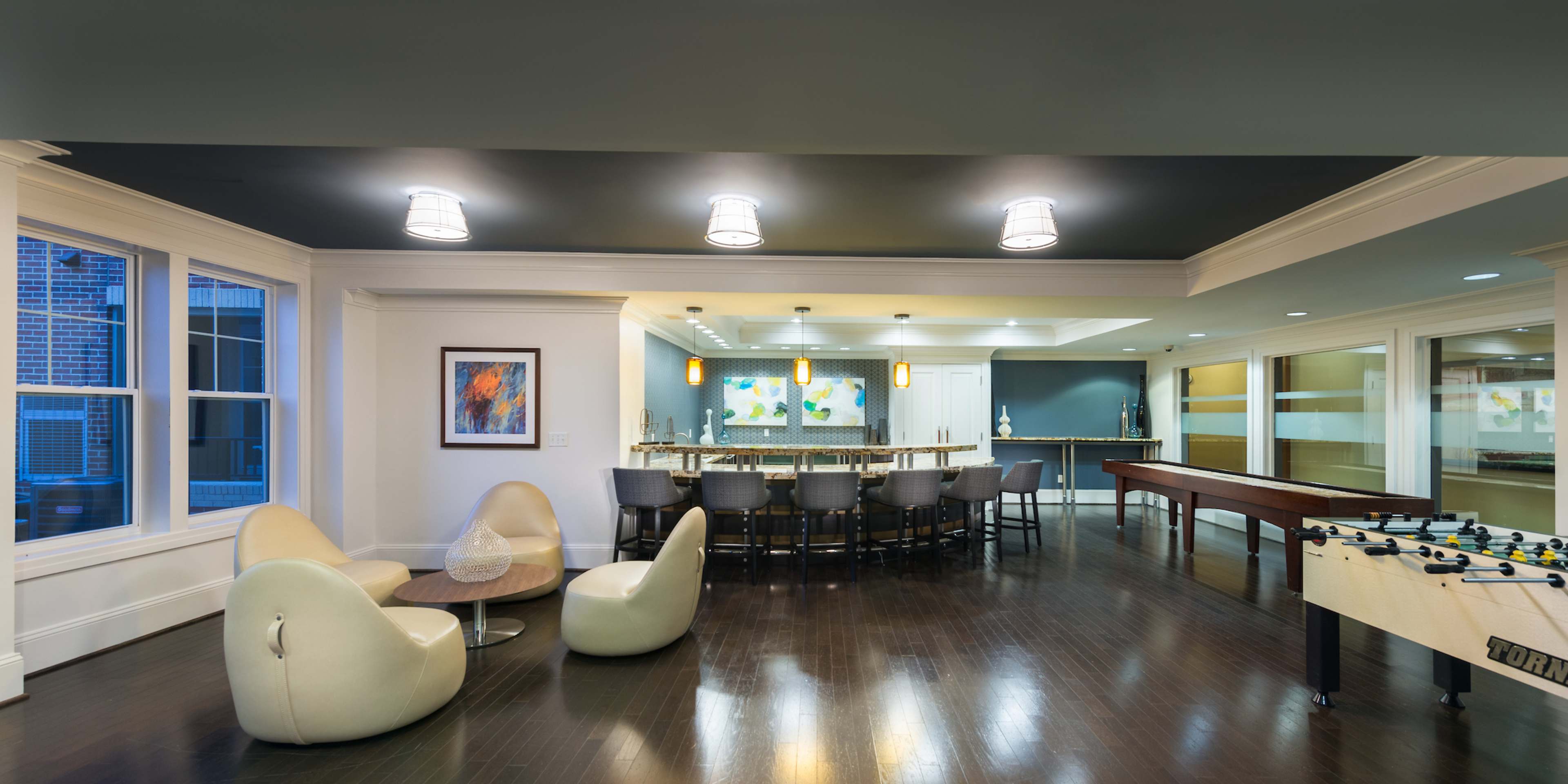 A modern lounge area with a bar, foosball table, and comfortable seating arranged around a coffee table.