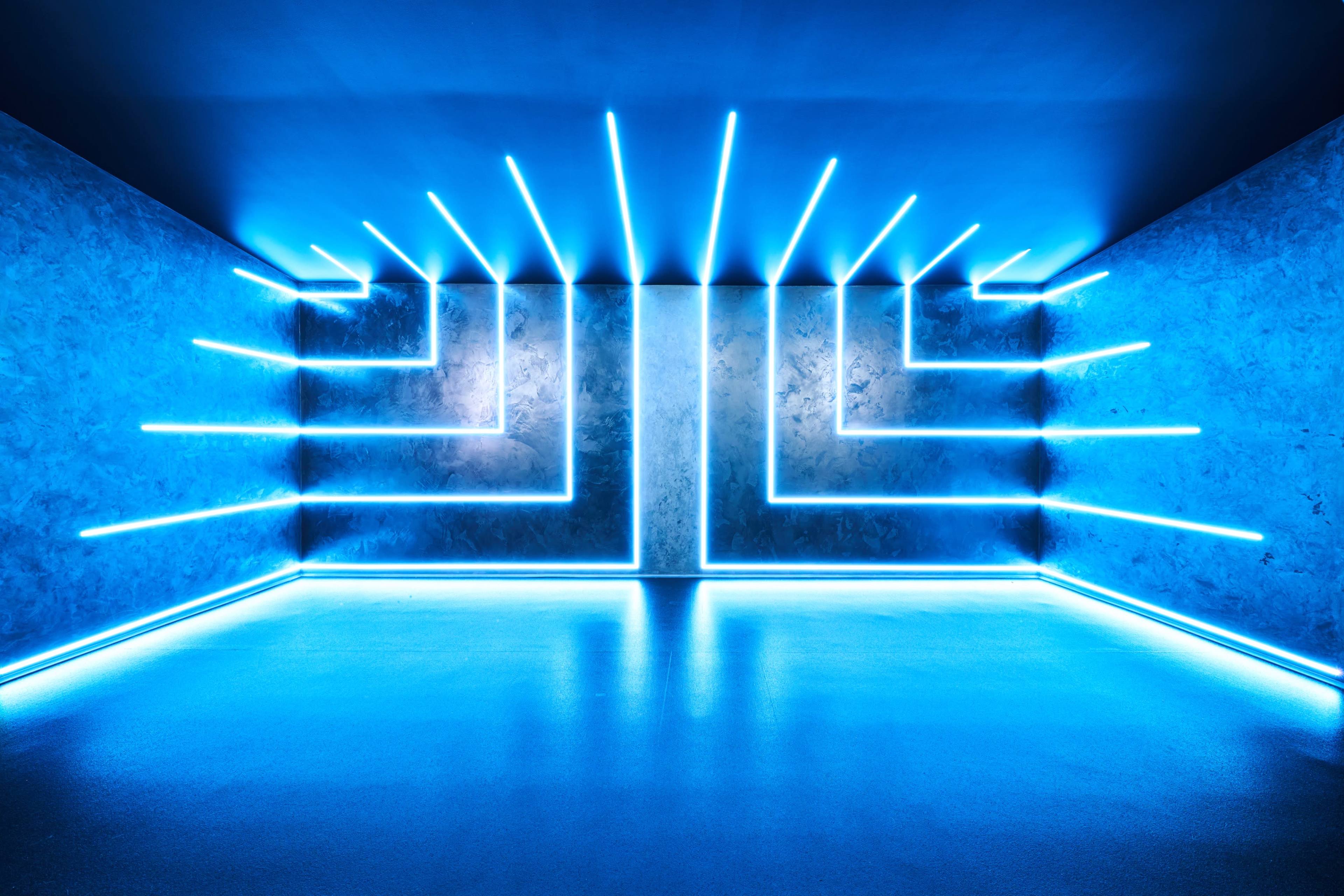 A room with blue neon lights arranged in a geometric pattern along the walls and floor.