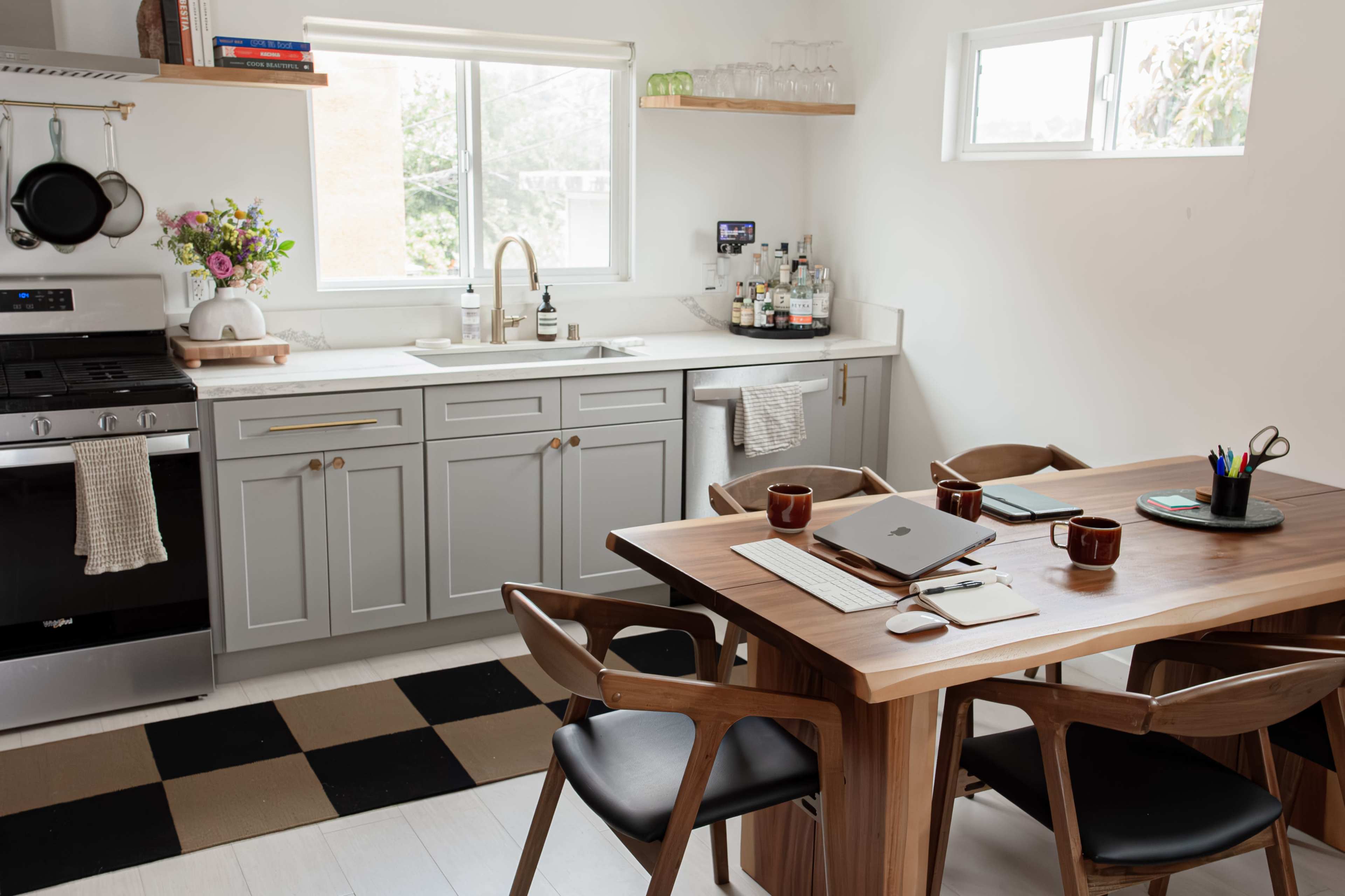 A modern kitchen with gray cabinetry, a center island, and a wooden dining table surrounded by four chairs.