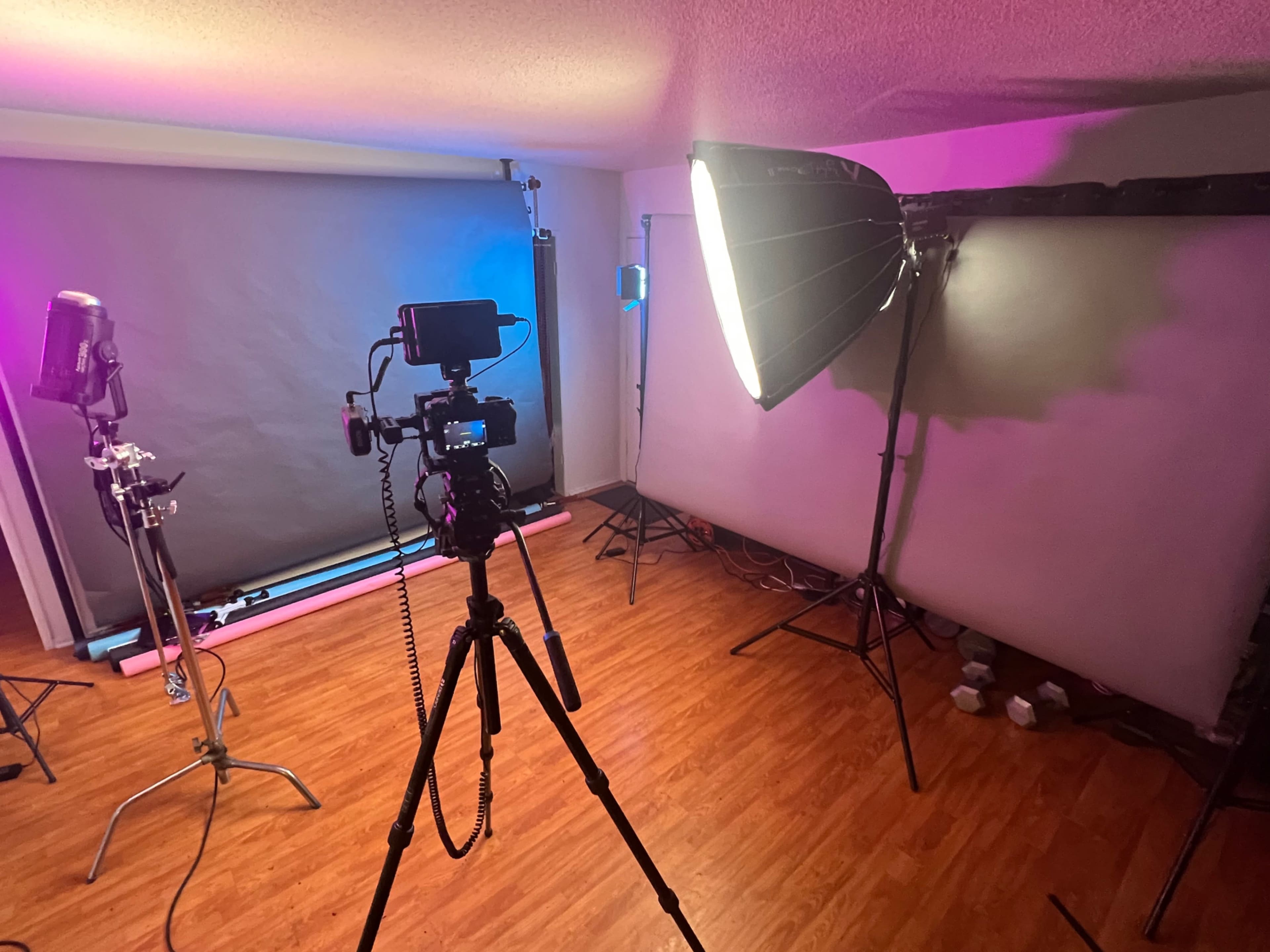 A photography studio setup with a camera on a tripod, light sources, and backdrop supports.