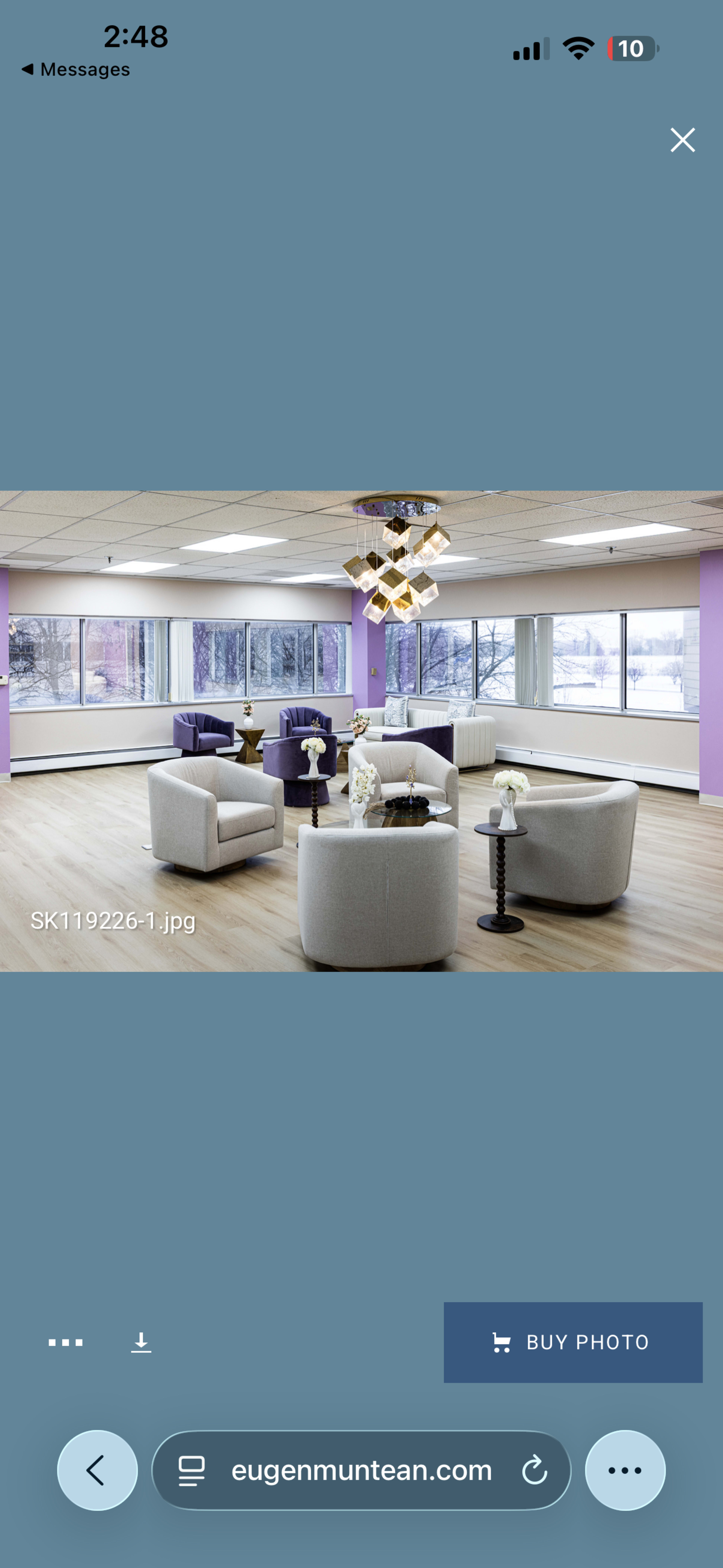 The image shows a modern lounge area with curvy chairs and tables, large windows allowing natural light, and purple accent walls.