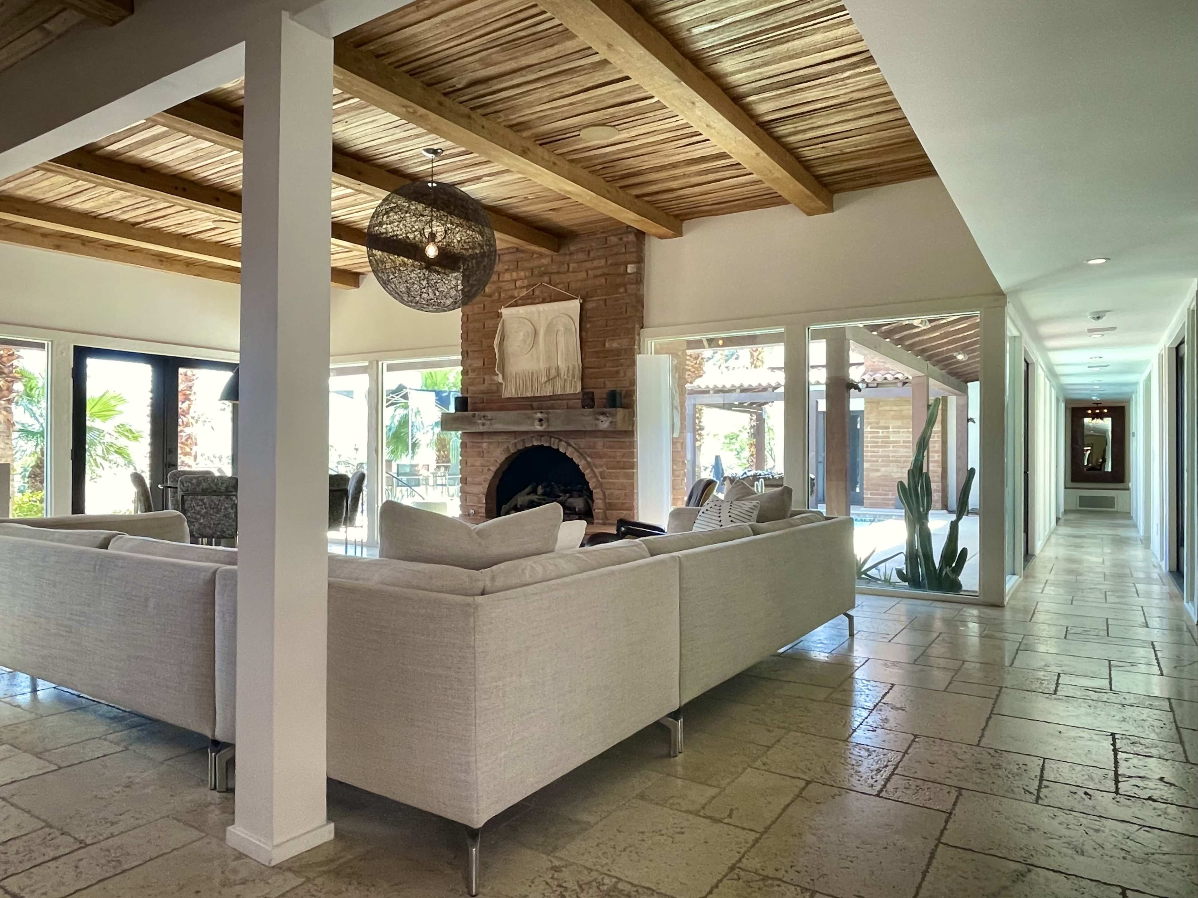 A spacious interior features a living area with a sectional sofa, a stone fireplace, and sliding glass doors leading to a patio.