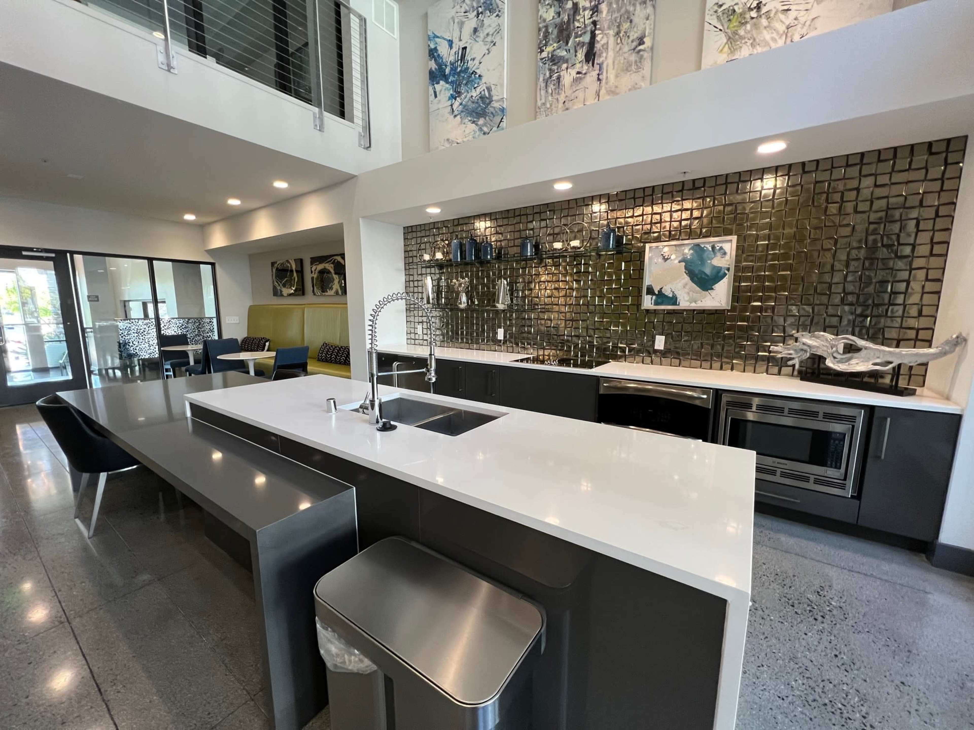 A modern kitchen with a large island, sleek cabinetry, stainless steel appliances, and a mosaic tile backsplash.