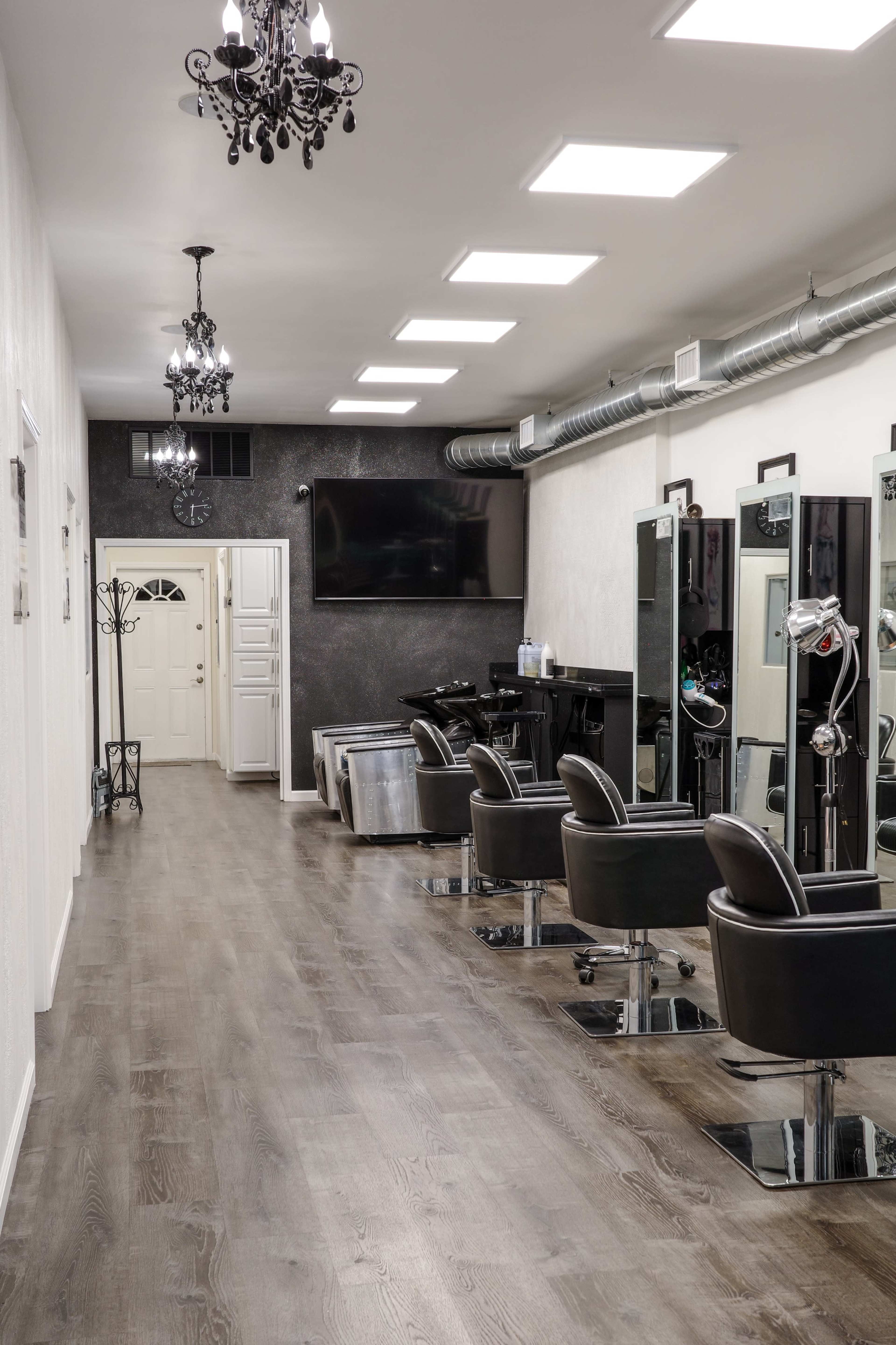 A well-lit hair salon with several black styling chairs and mirrors lining the walls.