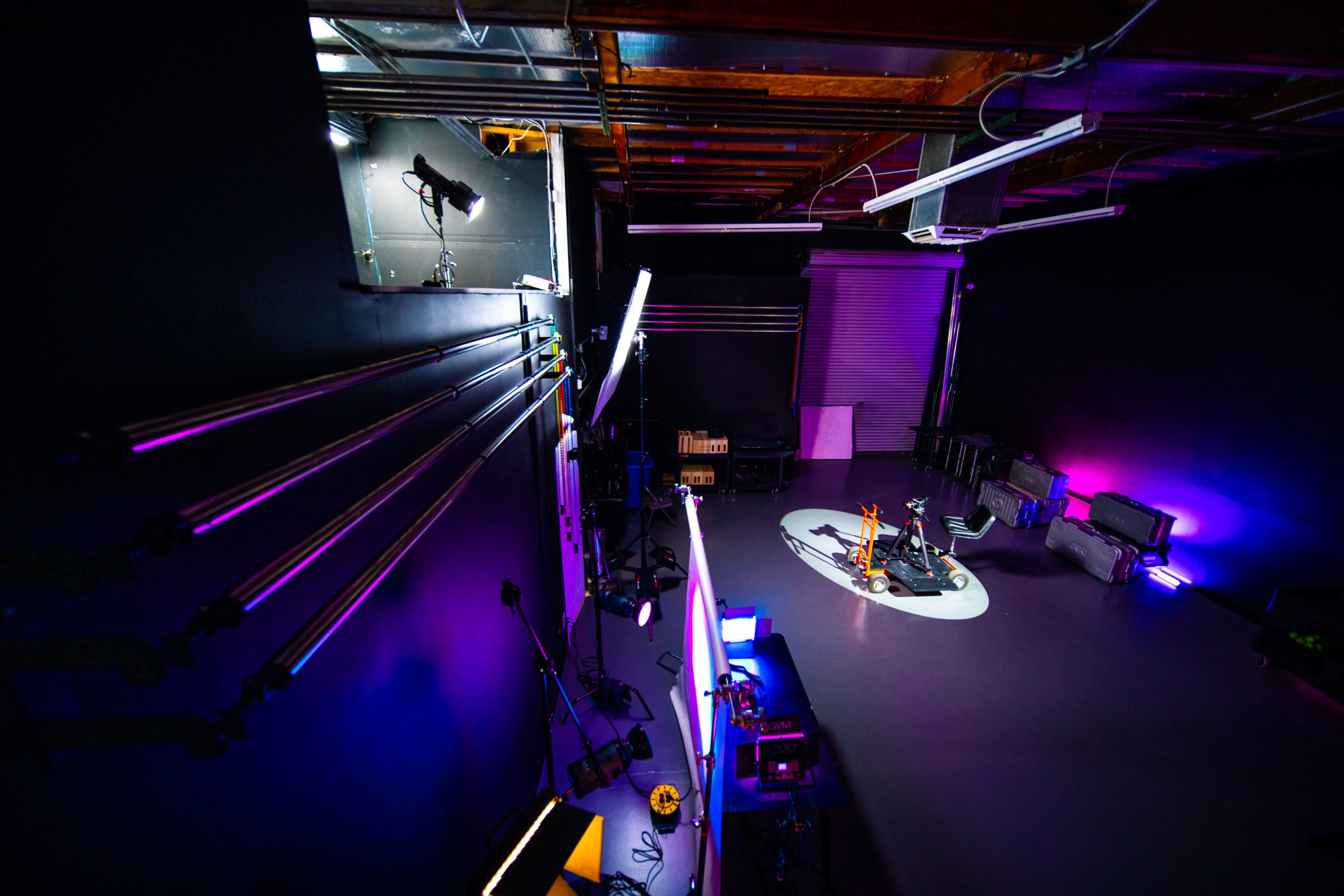 A photography studio with multiple lighting equipment set up around a central area on a polished floor.