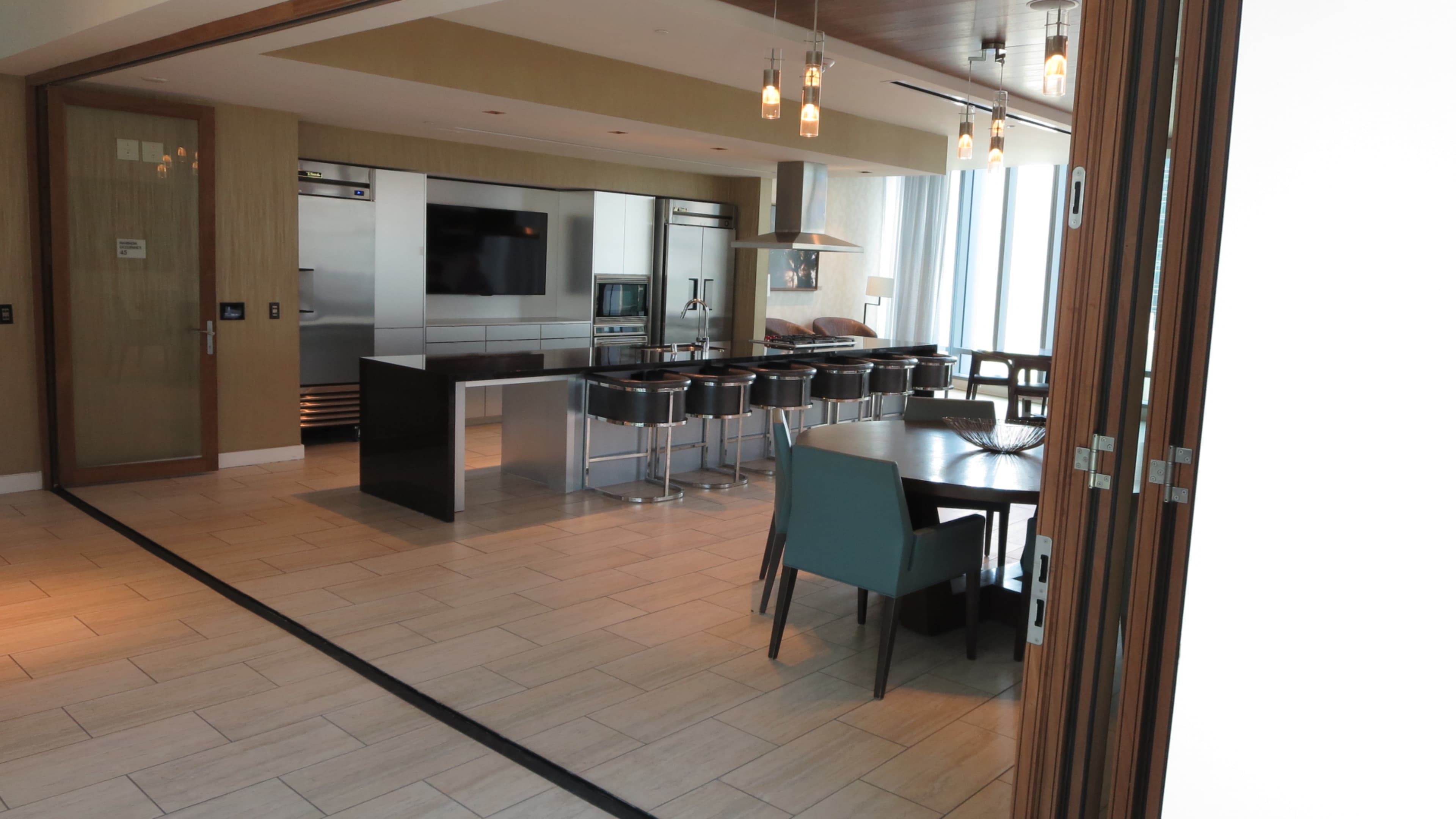 A modern kitchen and dining area with a central island, bar stools, and a dining table.