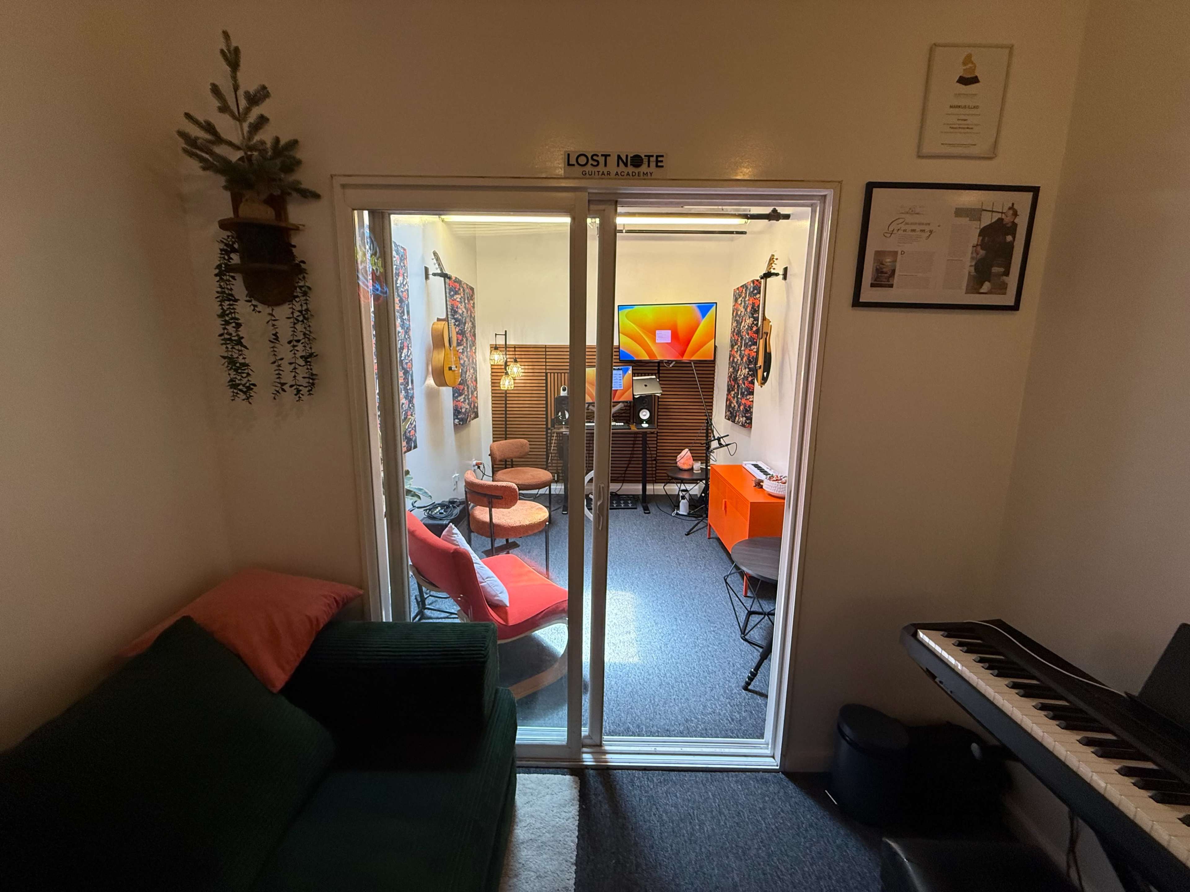 A small, brightly lit room is visible through double glass doors, featuring colorful decor, seating areas, and a television.