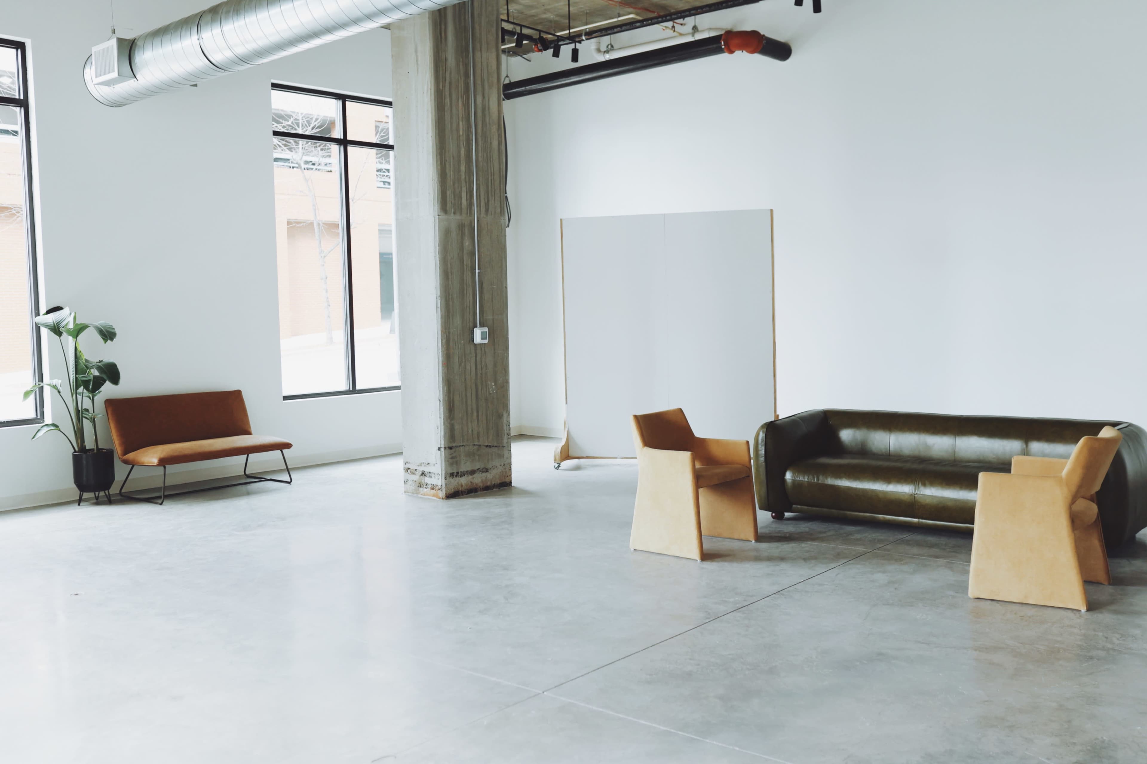 A spacious, minimalist interior with two different seating arrangements and large windows allowing natural light.