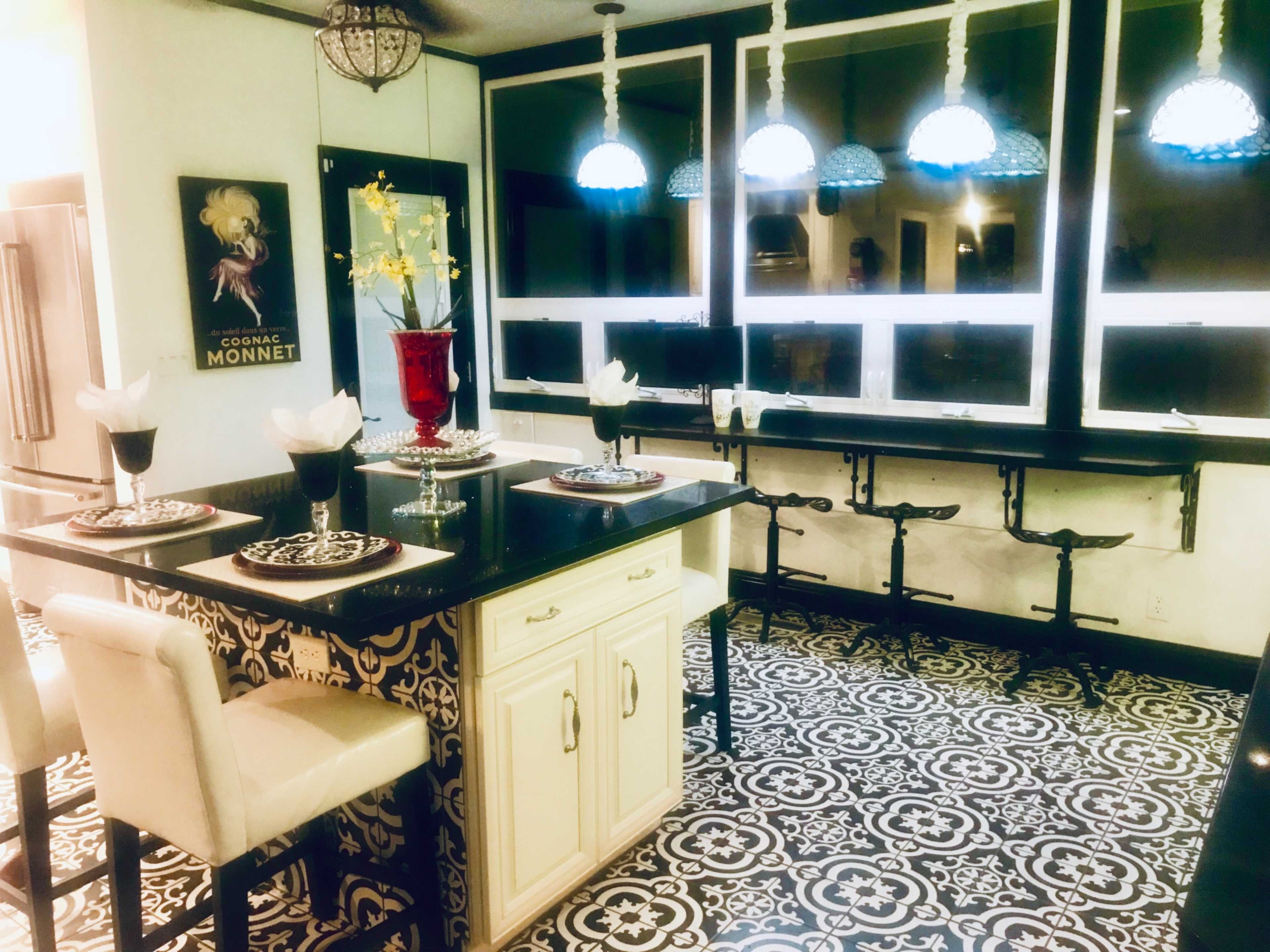 A kitchen with a patterned floor, an island with seating, and three blue pendant lights hanging above.