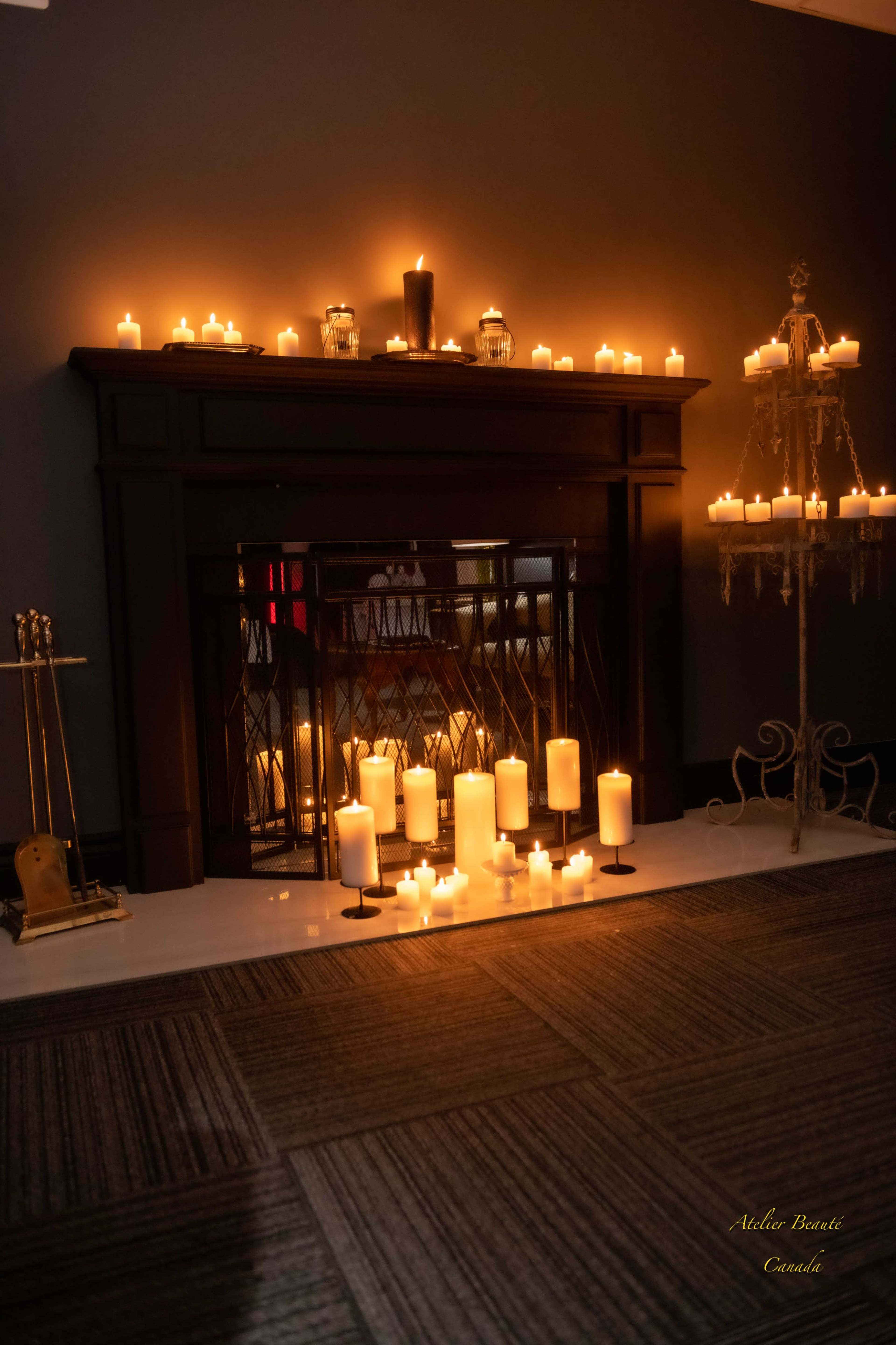 A fireplace adorned with numerous lit candles creates a warm and inviting atmosphere in a dimly lit room.