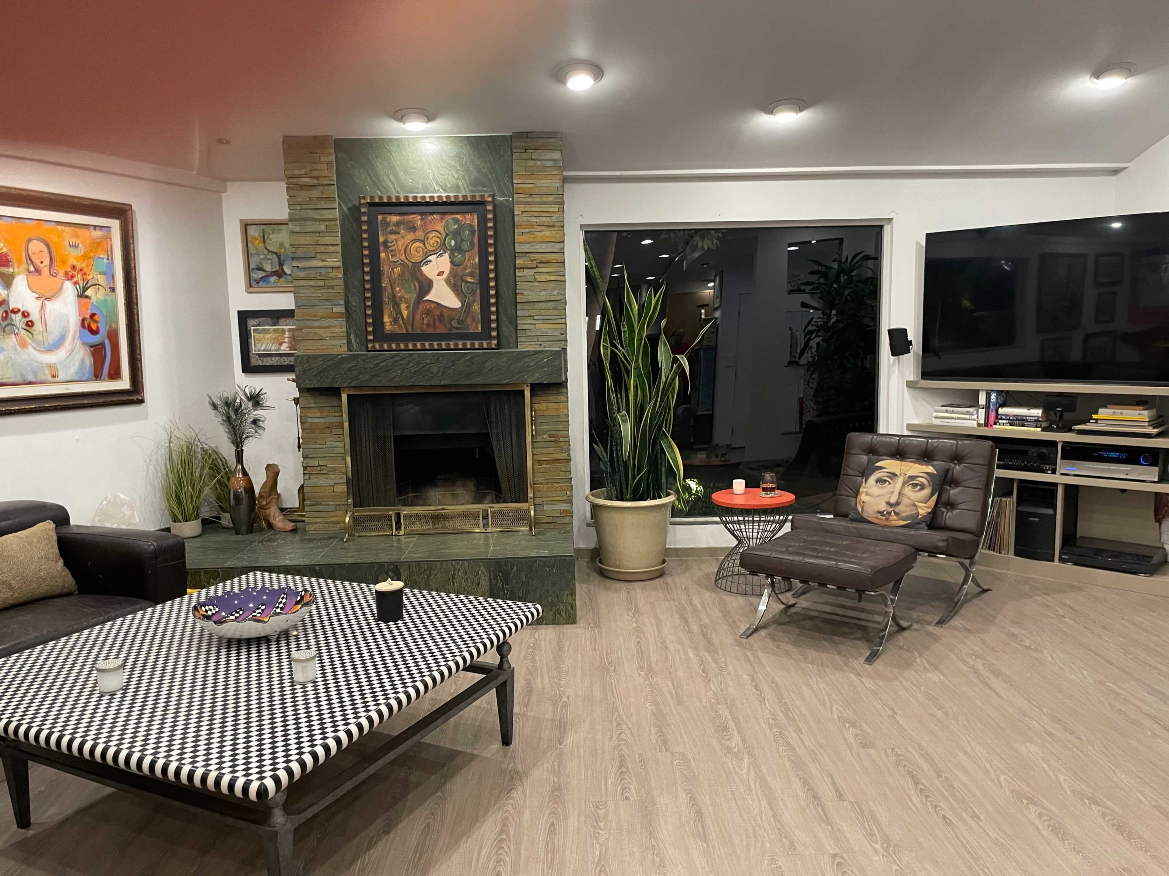 A living room featuring a stone fireplace, modern furniture, and artwork on the walls.