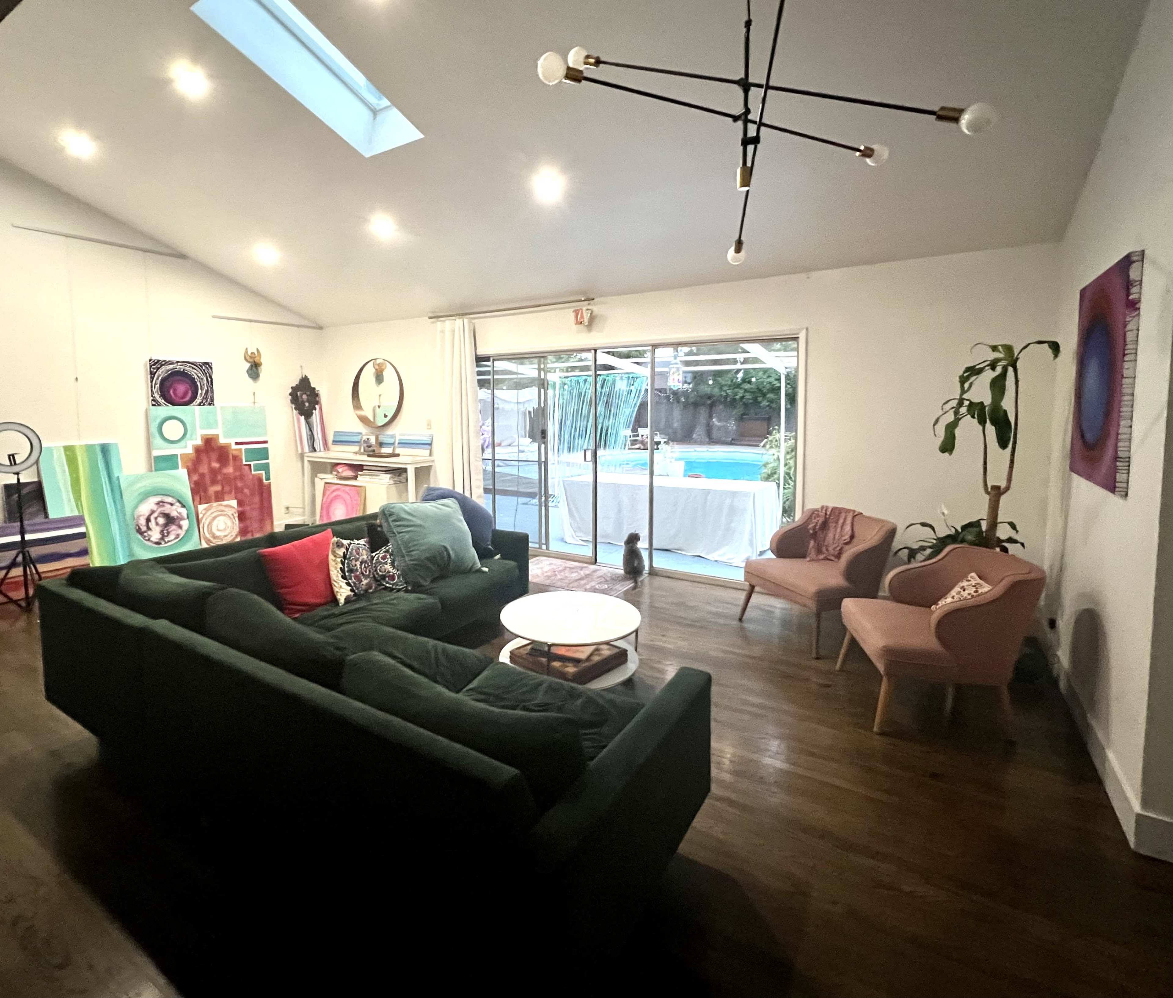A modern living room features a sectional sofa, chairs, and a large glass door leading to a pool area.