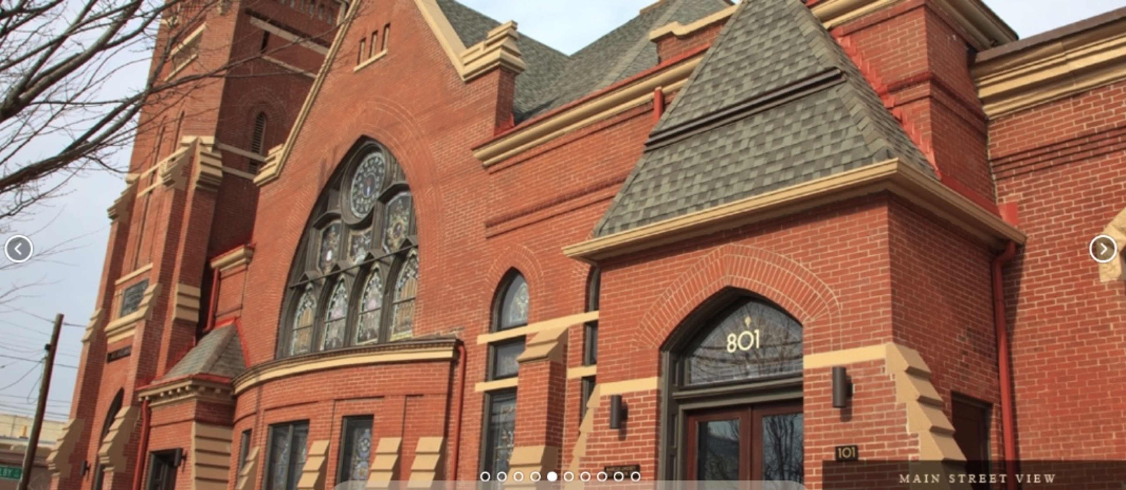 The exterior of a large brick building featuring arched windows and a prominent entrance.