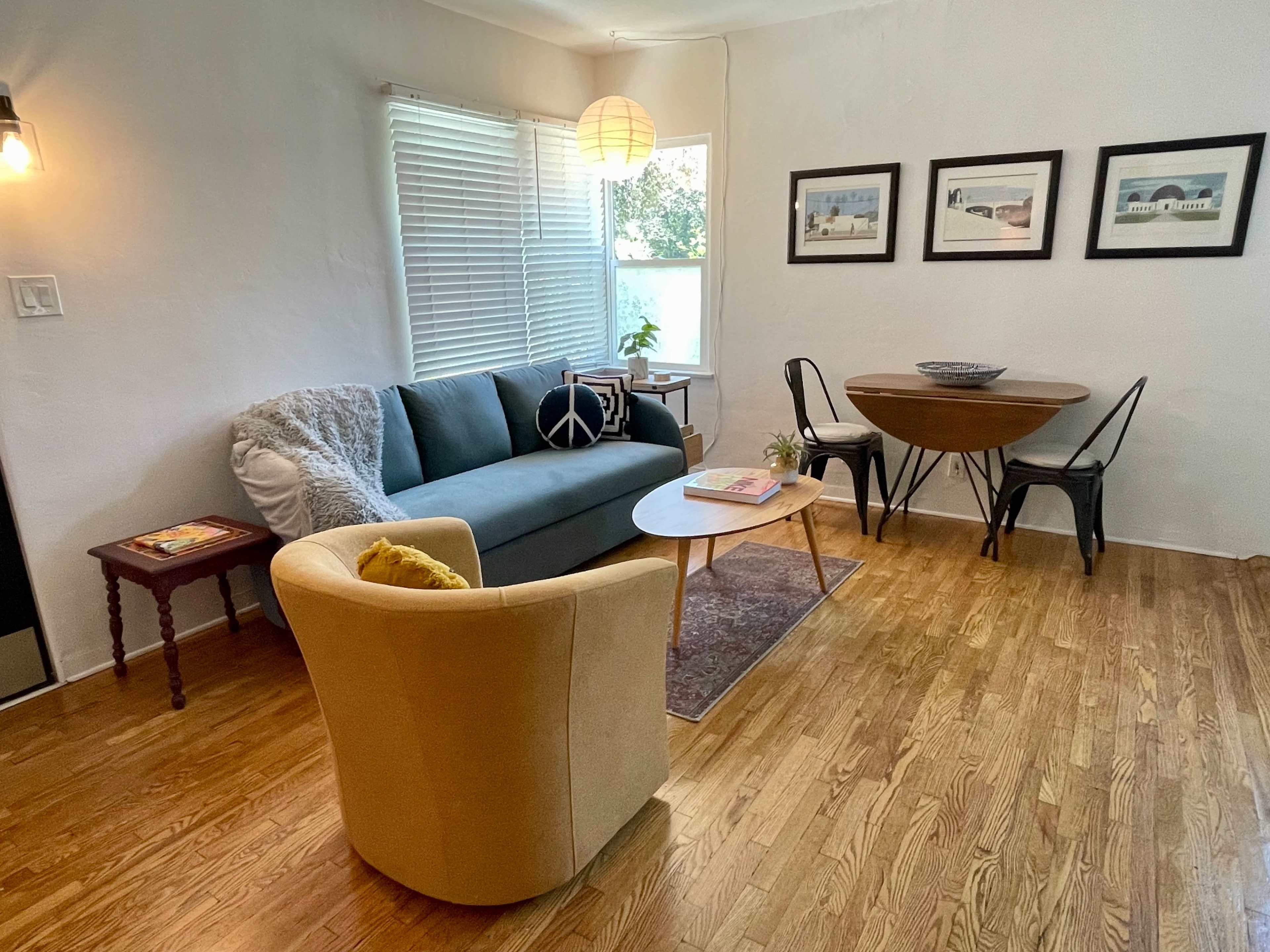 A cozy living space with a green sofa, a round dining table, and framed pictures on the wall.