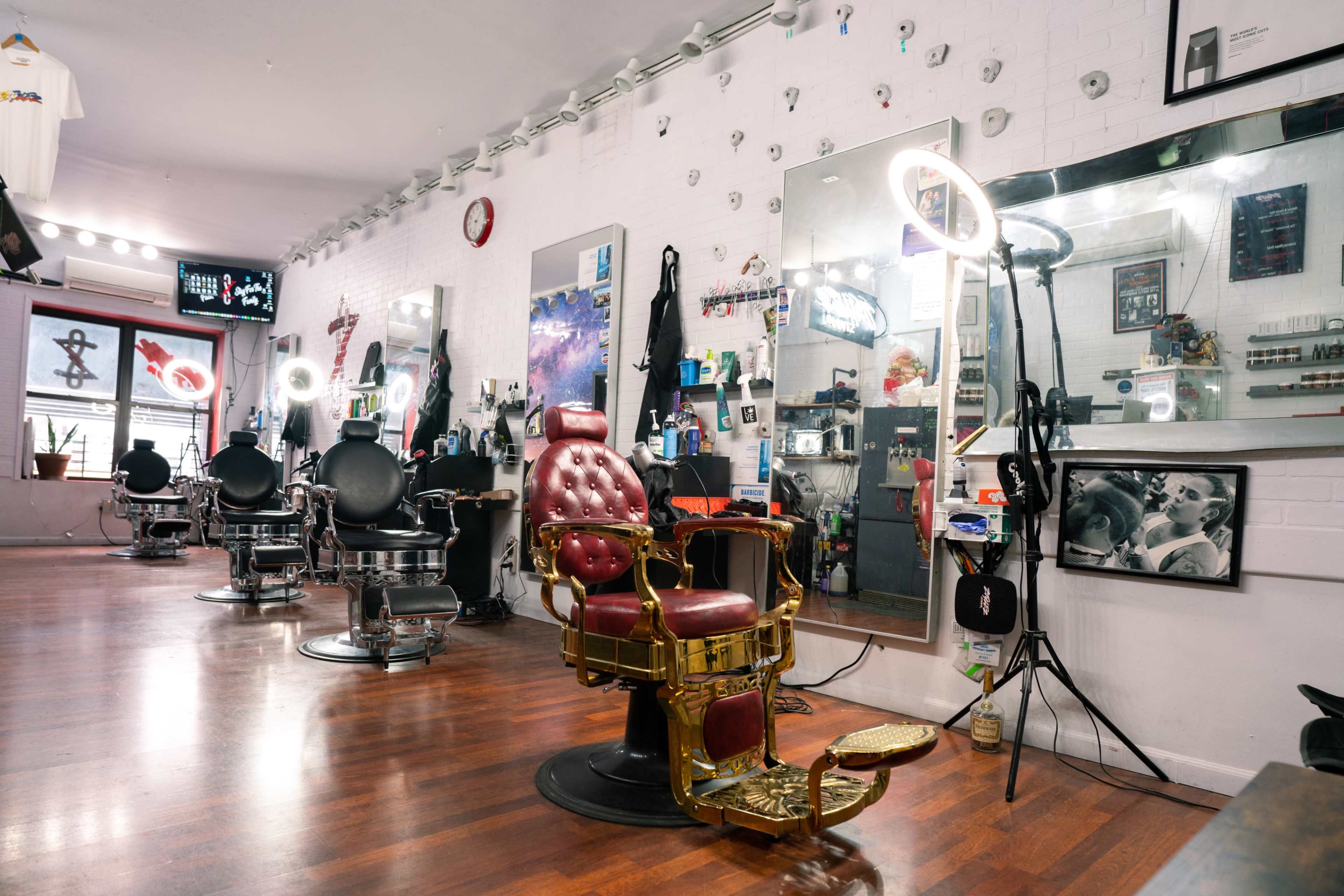 The image shows the interior of a barber shop with multiple styling chairs, large mirrors, and well-organized tools.