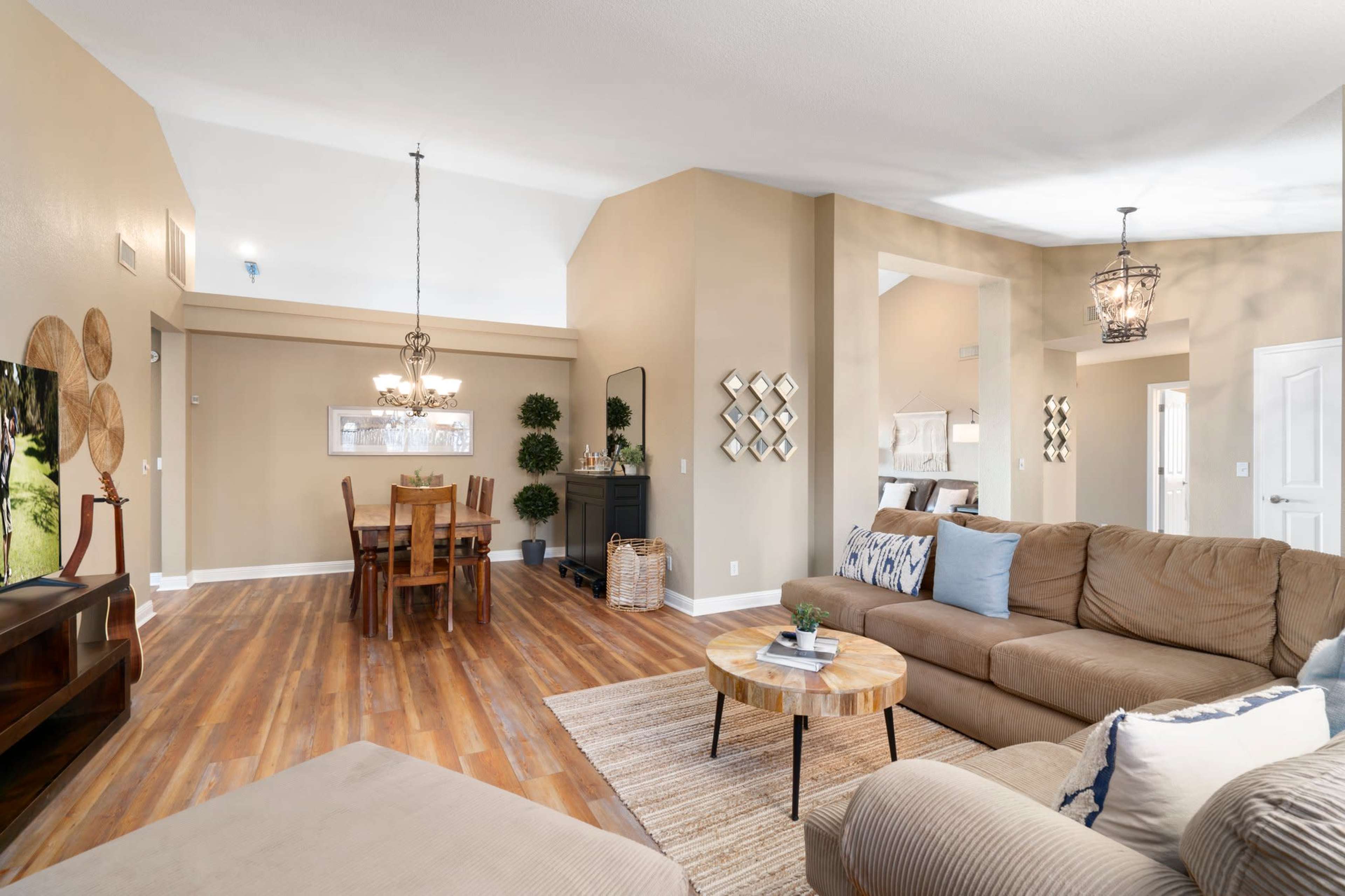 A spacious living area with a couch, coffee table, and dining table in a well-lit open floor plan.