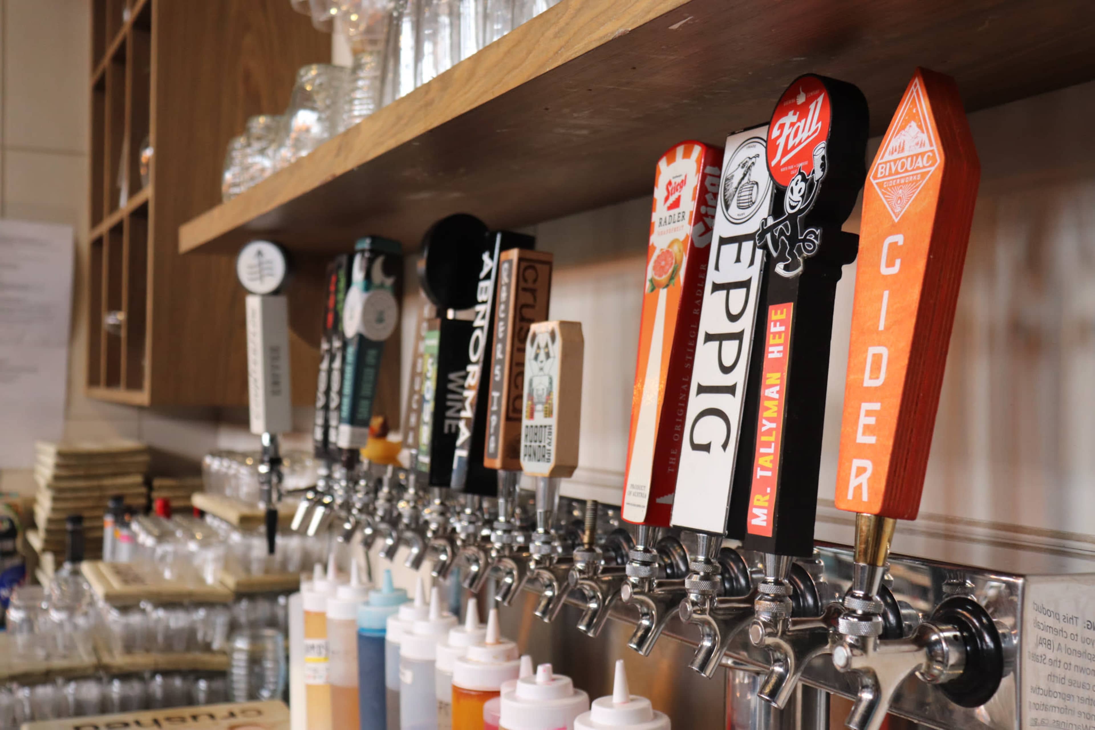 A row of beer taps featuring various brands and types of beverages at a bar.