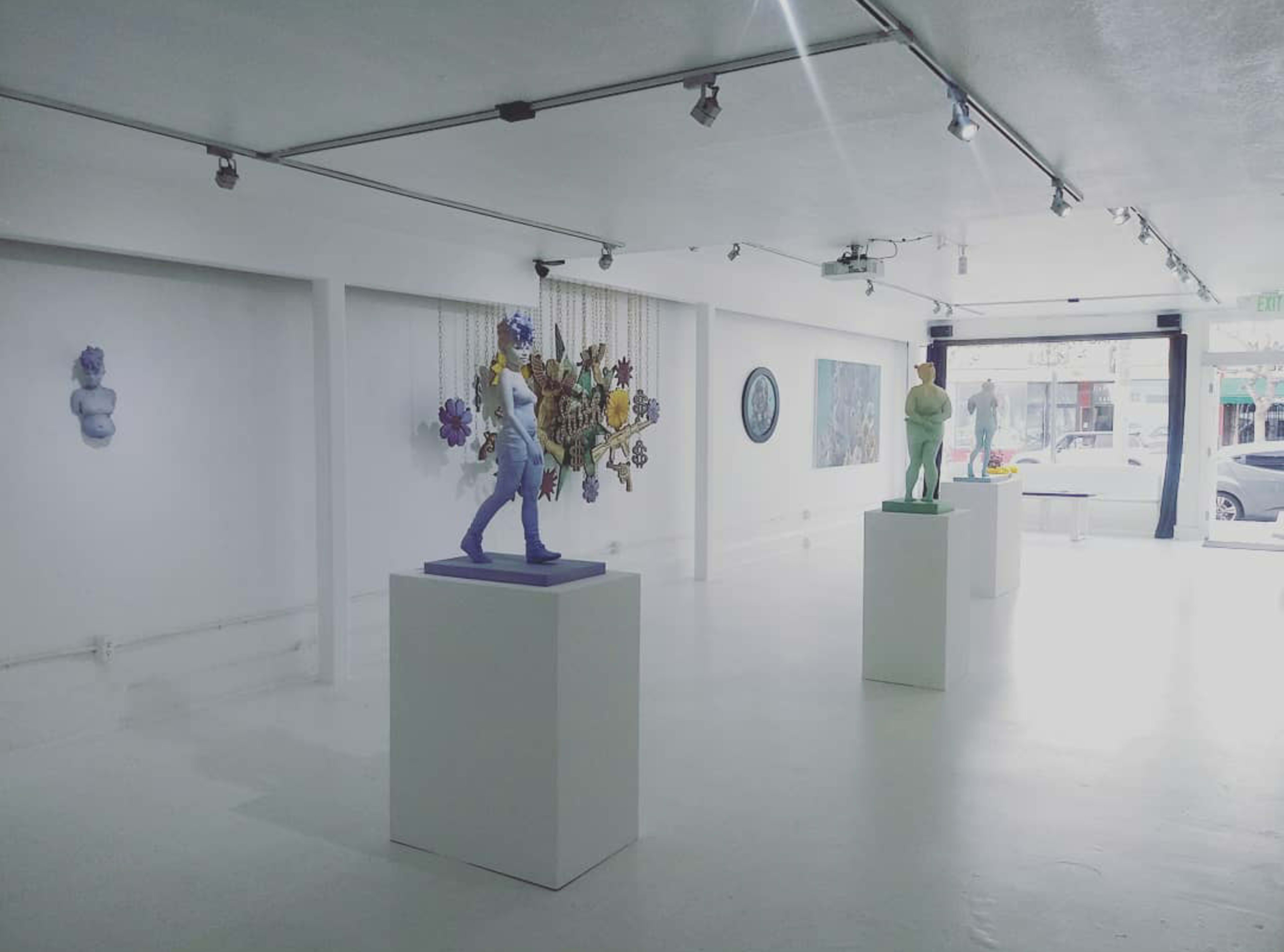 An art gallery featuring several sculptures displayed on pedestals against white walls.