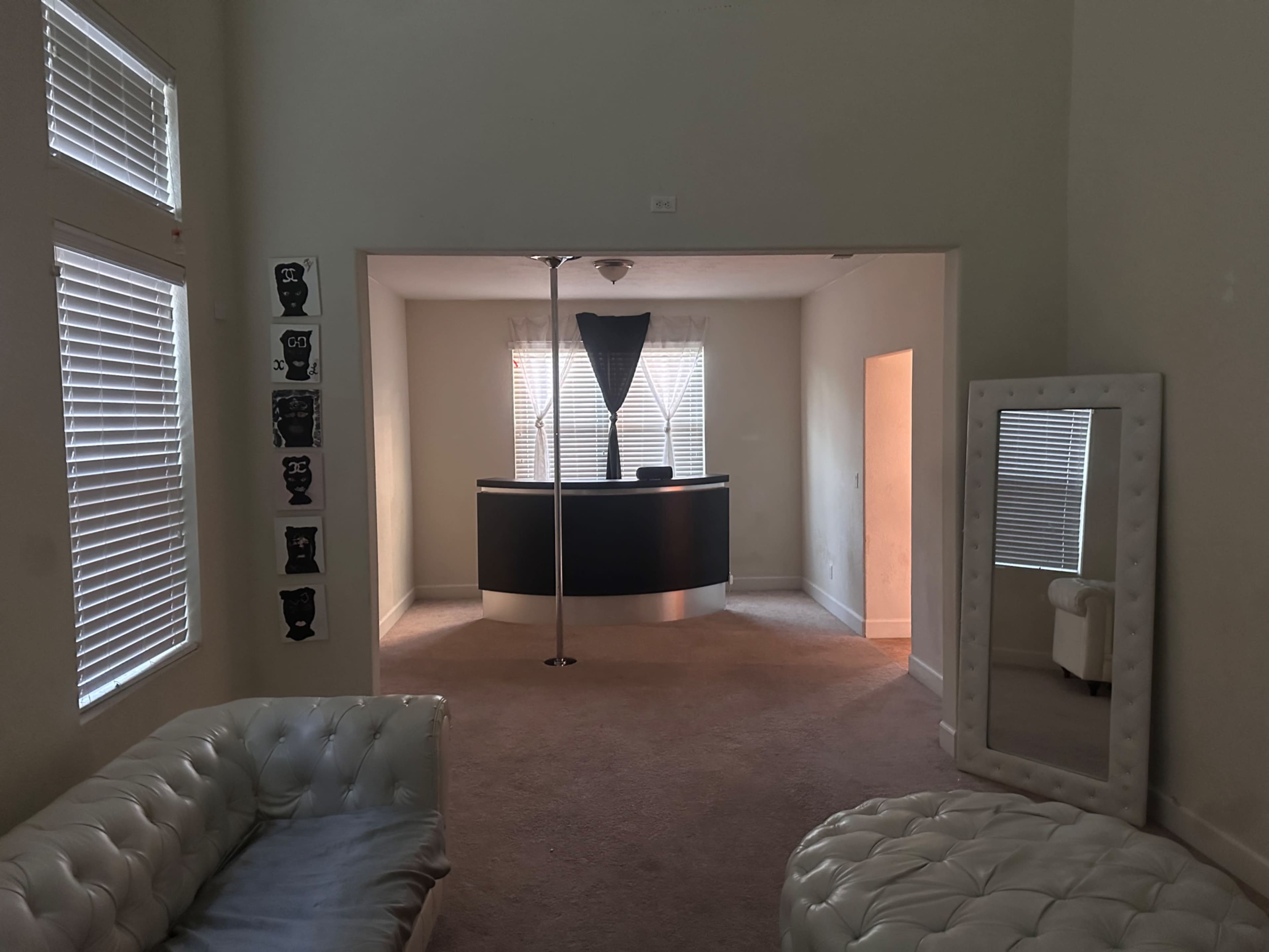 A spacious room featuring a reception desk with a curved design, a pole in the center, and a seating area with white furniture.