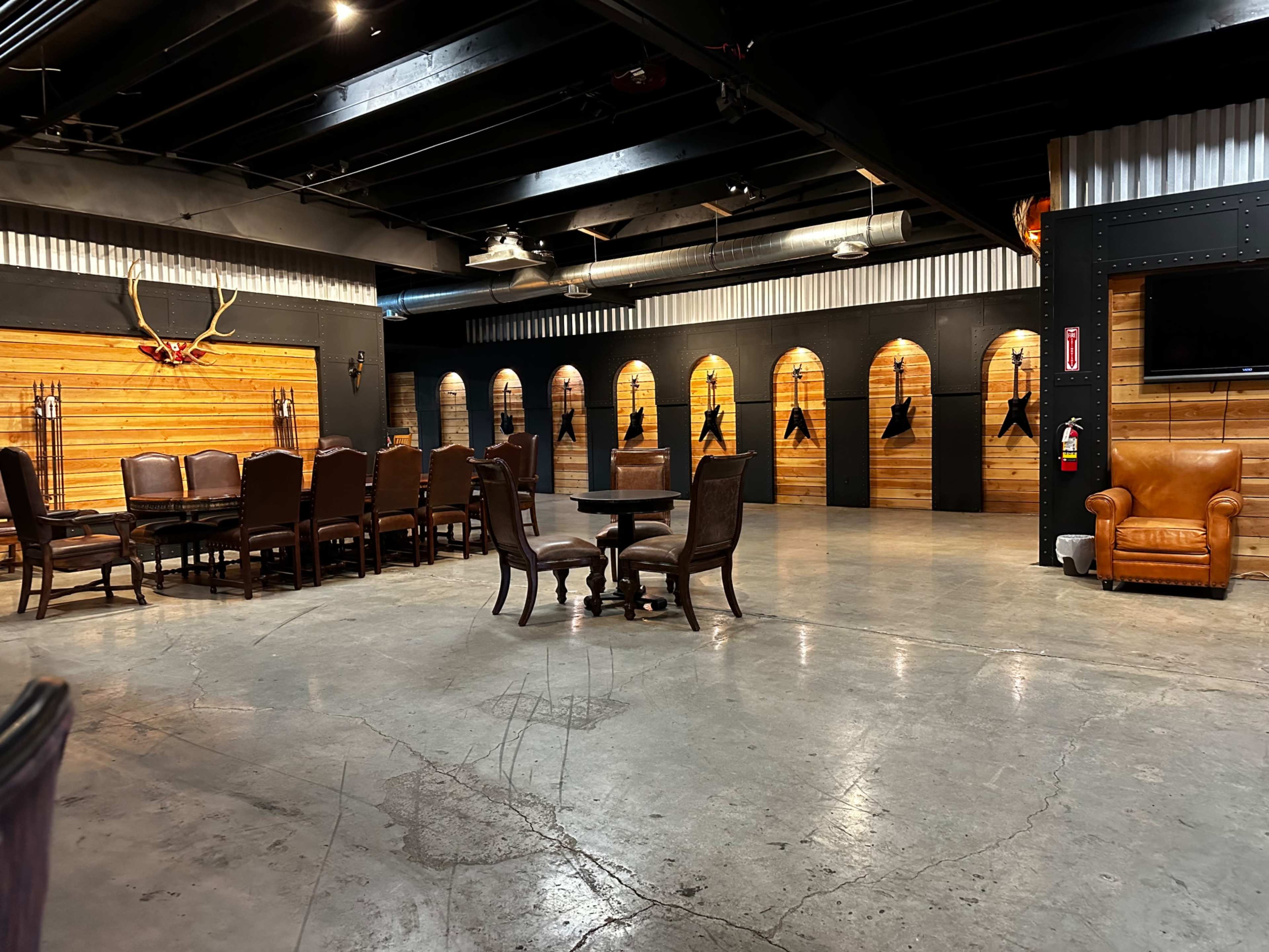 A spacious interior of a rustic-themed room with wooden walls, several dining tables and chairs, and taxidermy displays.