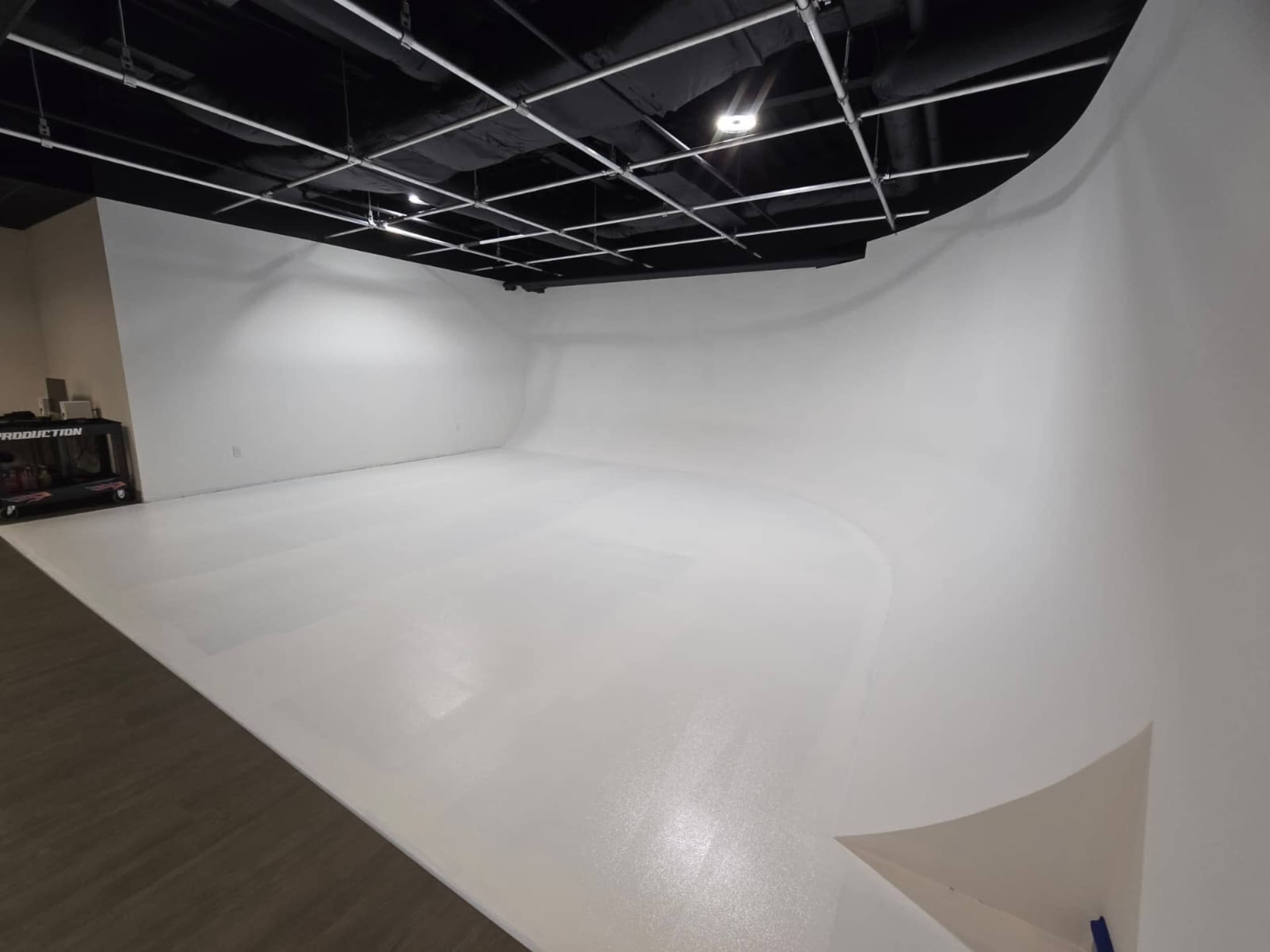 The image shows a spacious studio with a seamless white backdrop and a smooth floor, designed for photography or filming.
