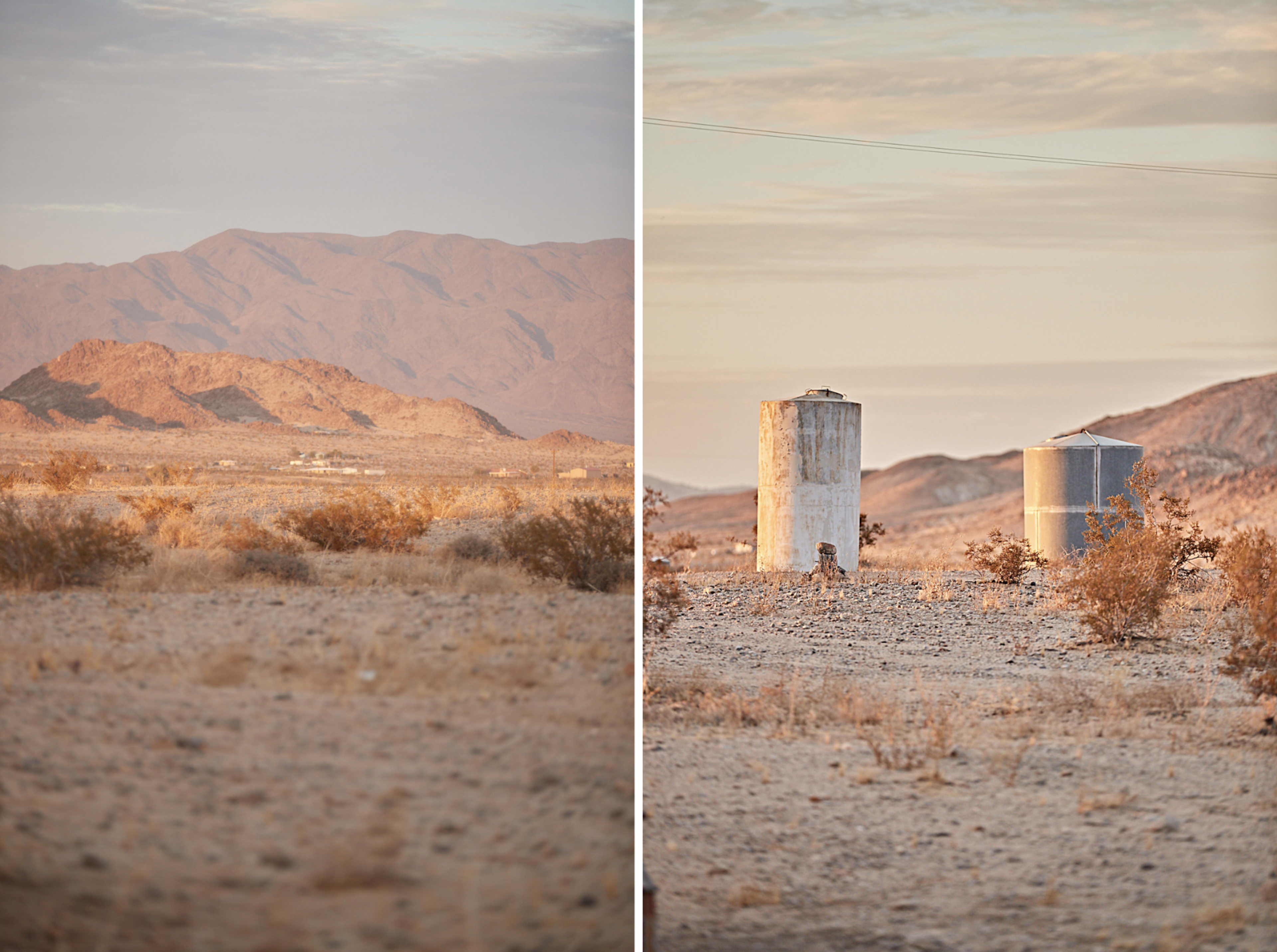 A barren desert landscape with mountains in the background and two cylindrical water tanks in the foreground.