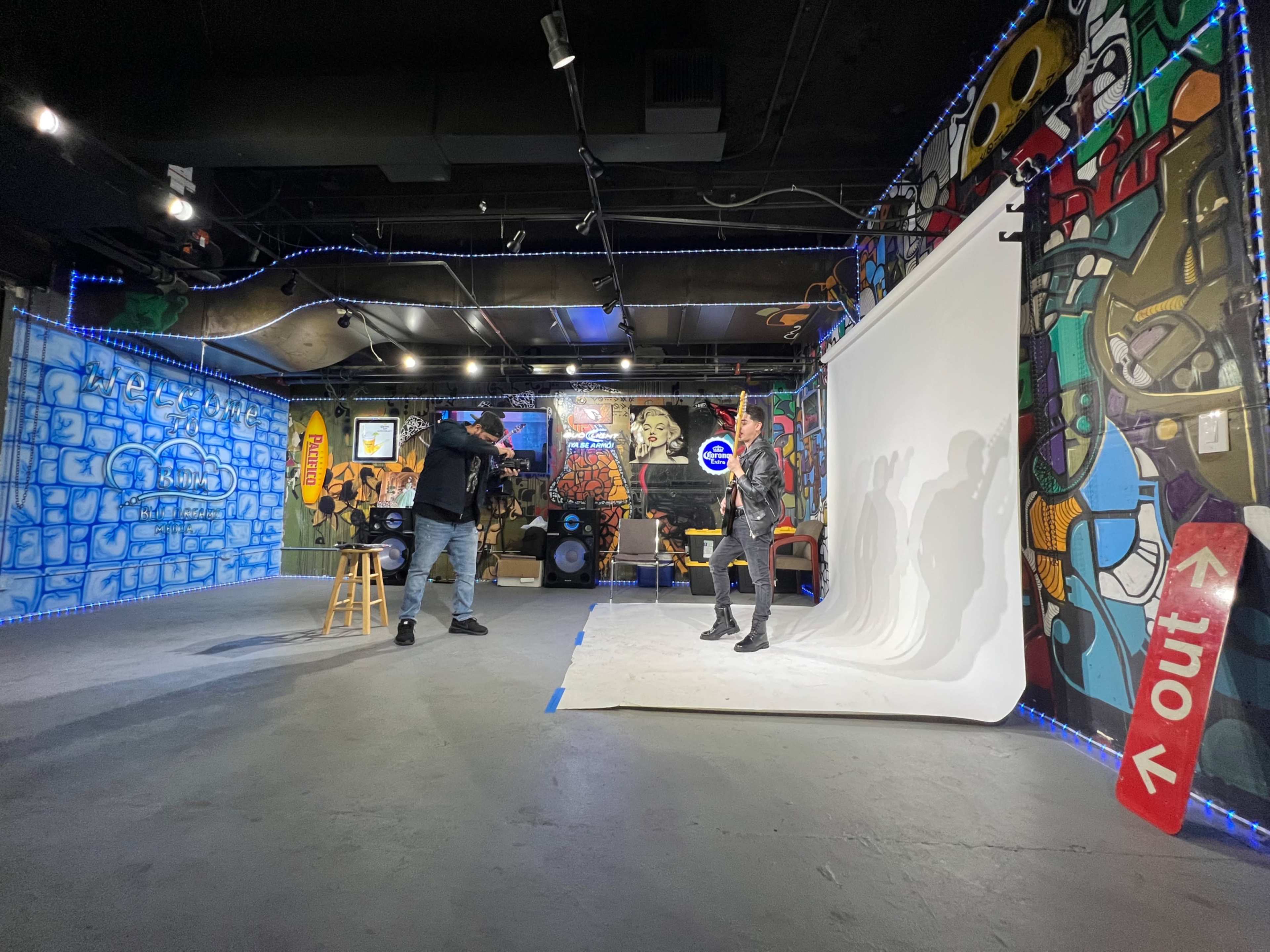 A photographer captures a model posing against a white backdrop in a creatively decorated studio featuring colorful murals.