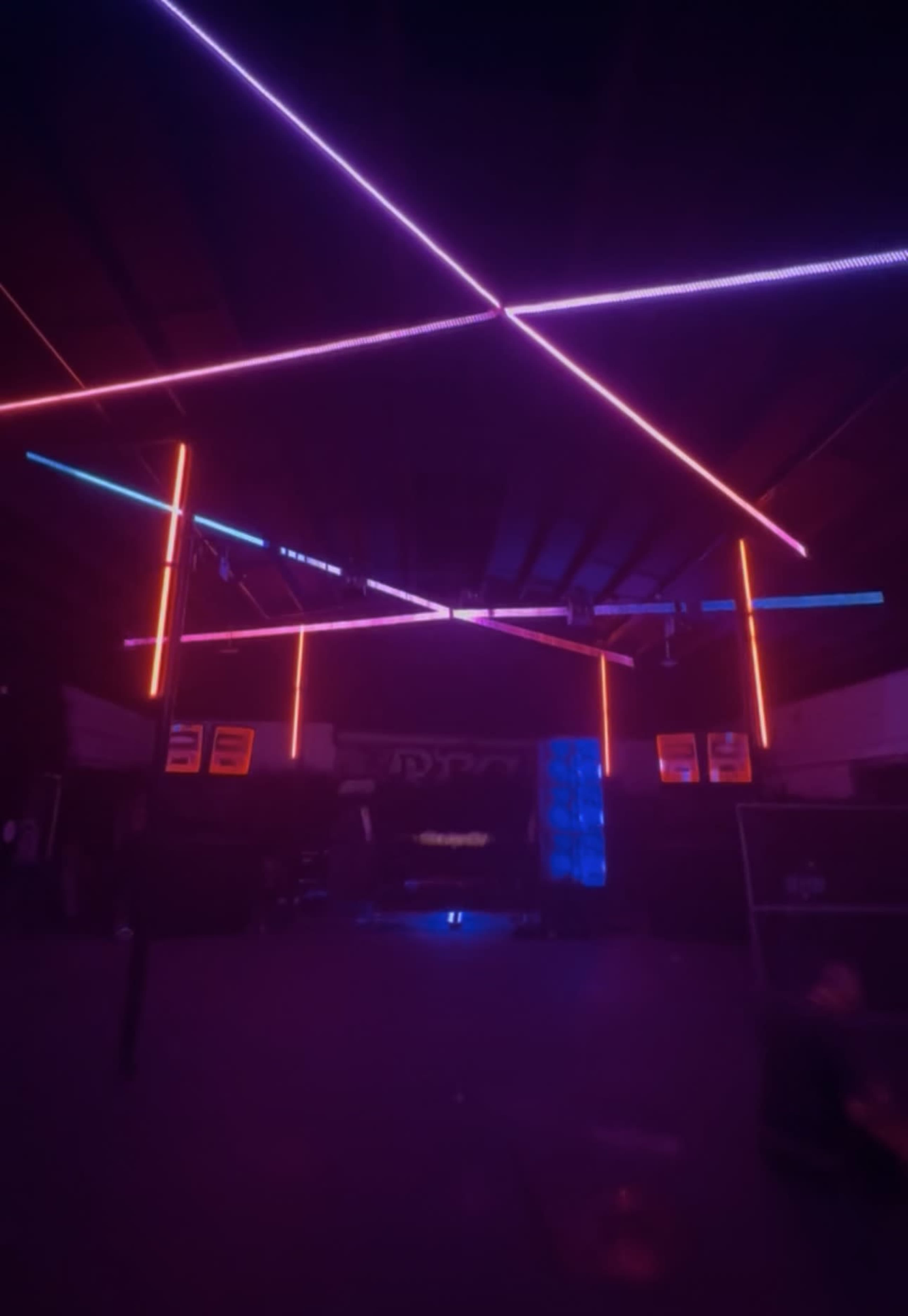 The image features an indoor space with colored neon lights arranged in a geometric pattern across the ceiling.