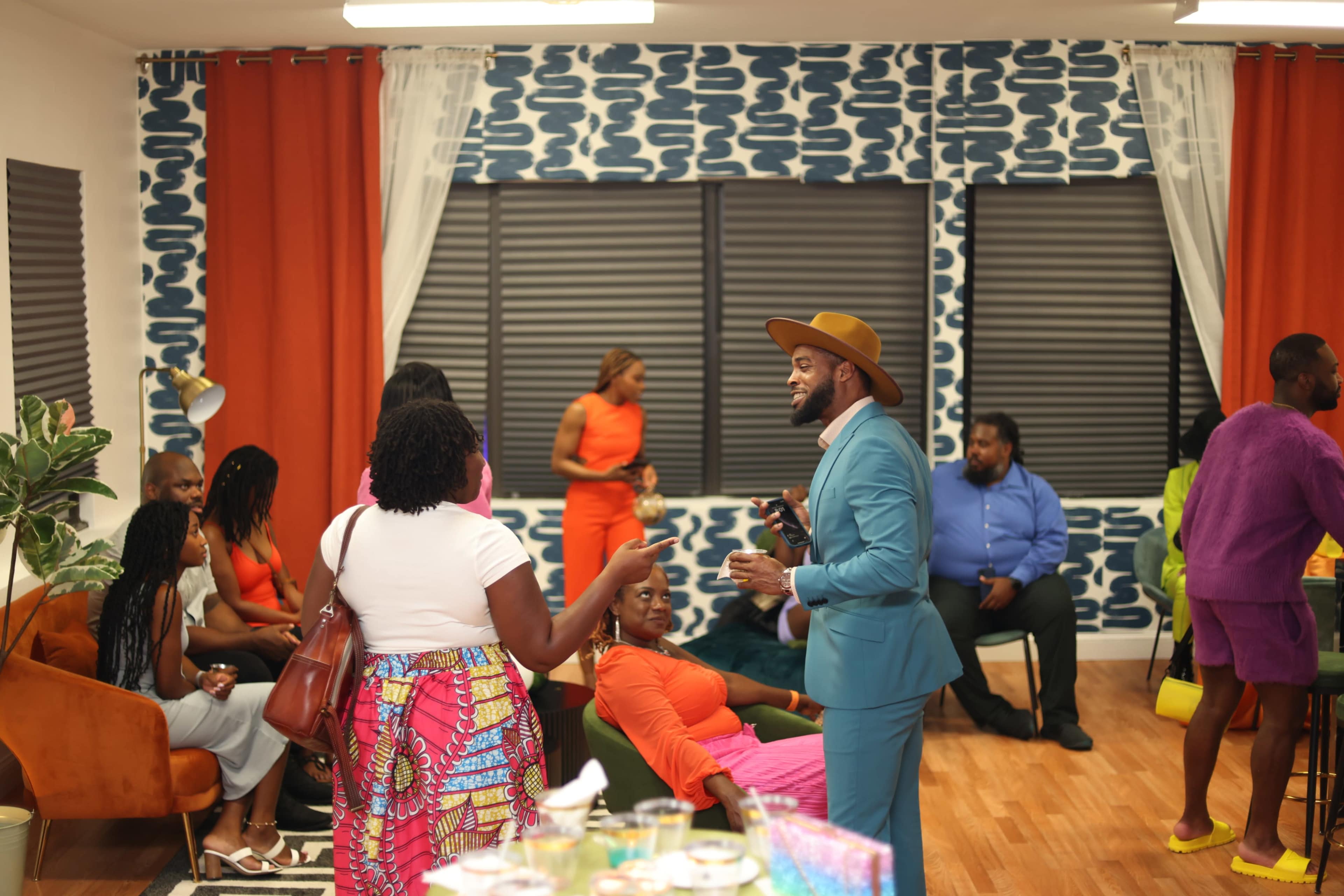 A group of people socialize in a brightly decorated room with patterned walls and colorful furnishings.