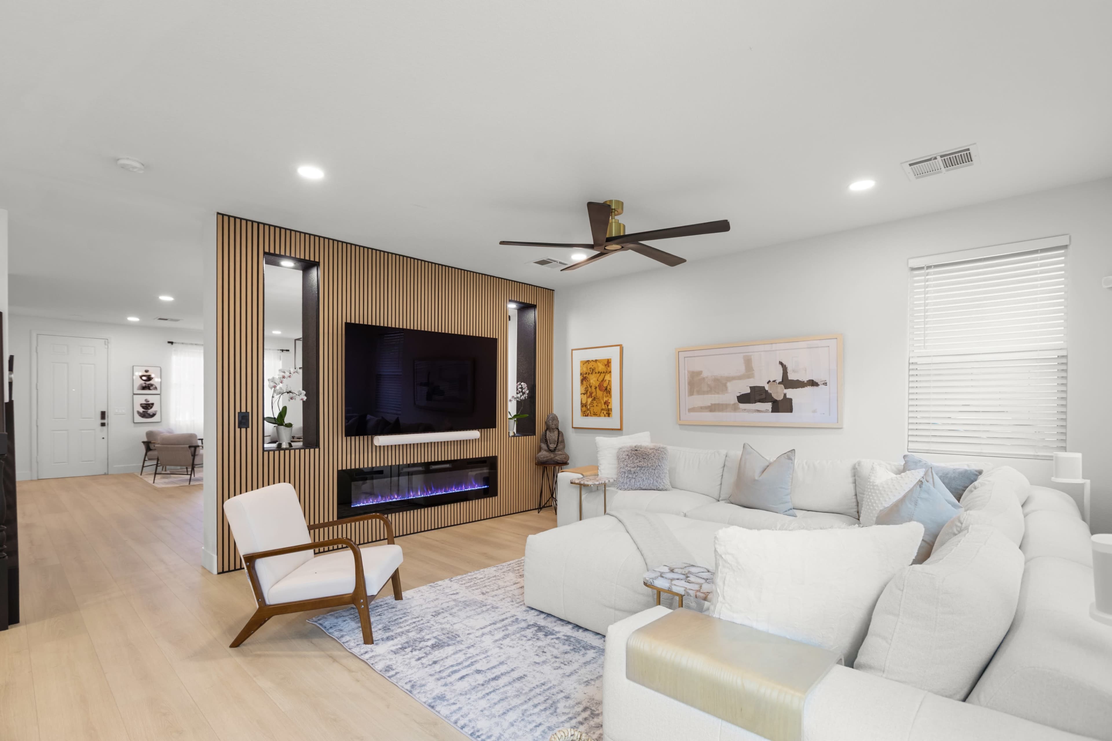 The image shows a modern living room featuring a sectional sofa, a wall-mounted television, and decorative artwork.