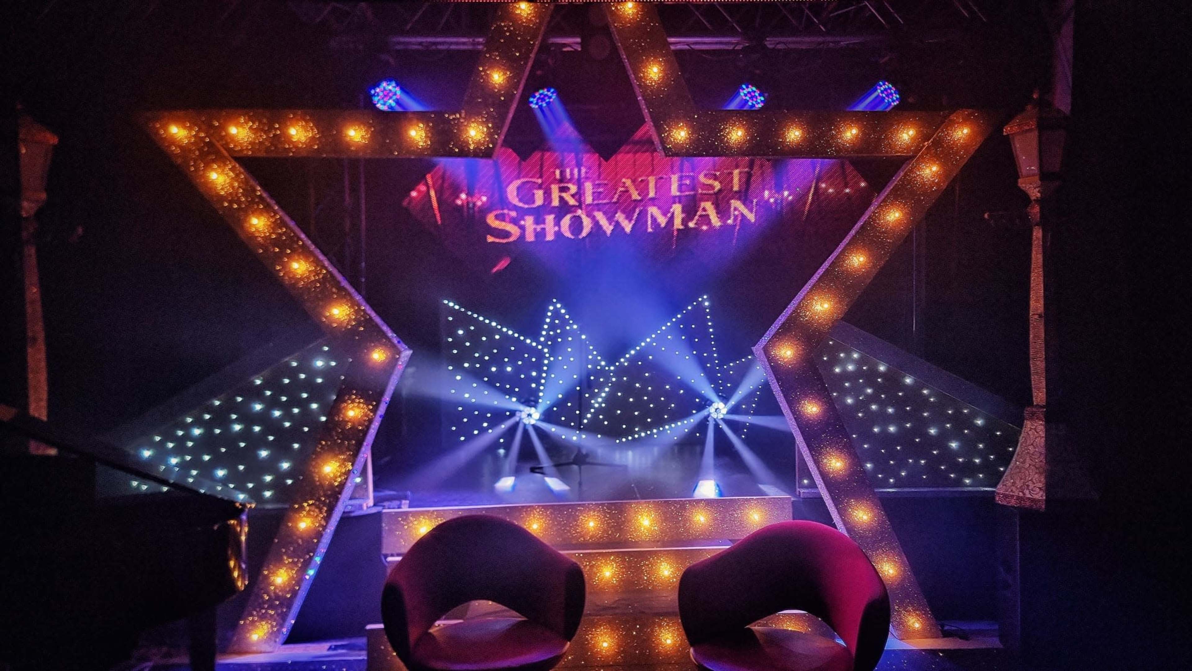 A stage designed in the shape of a star, featuring lights and a backdrop for "The Greatest Showman."
