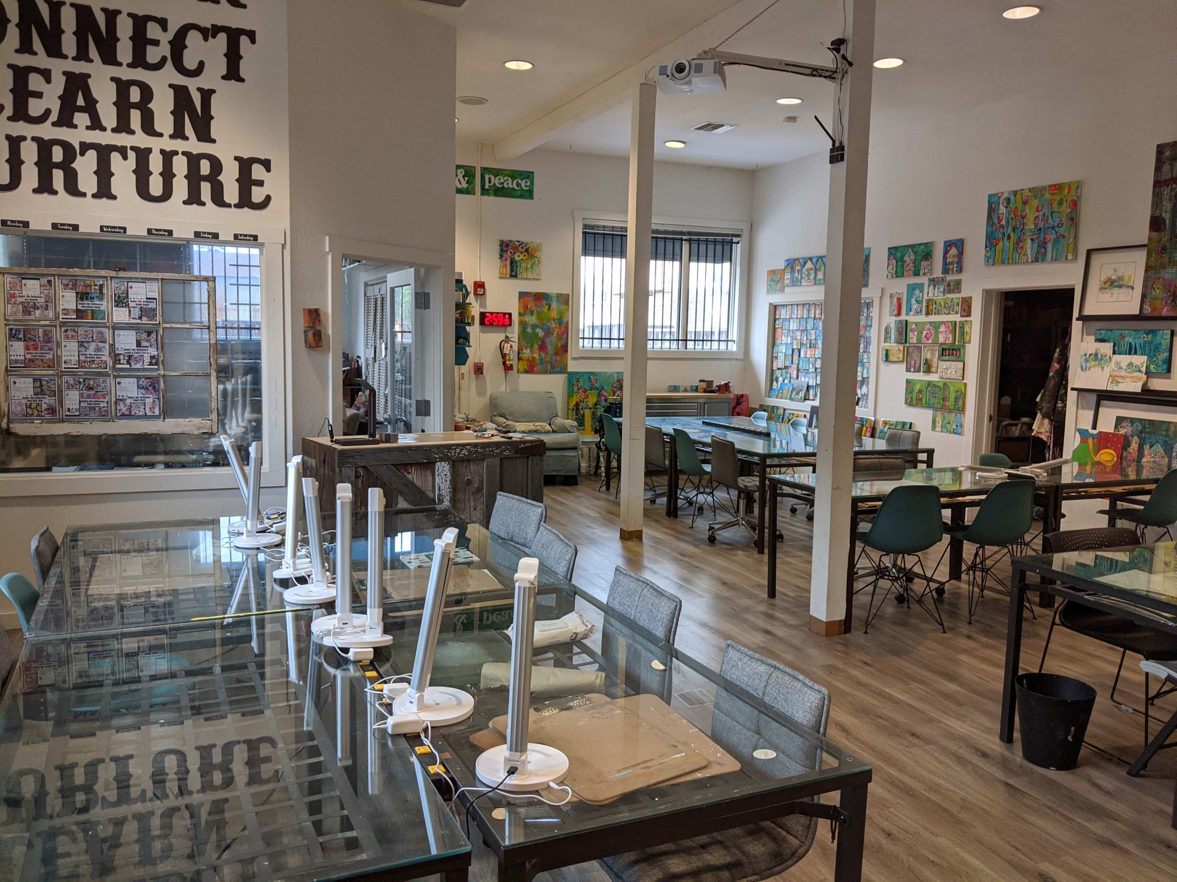 A spacious art classroom with several tables and chairs, displaying colorful artwork on the walls.