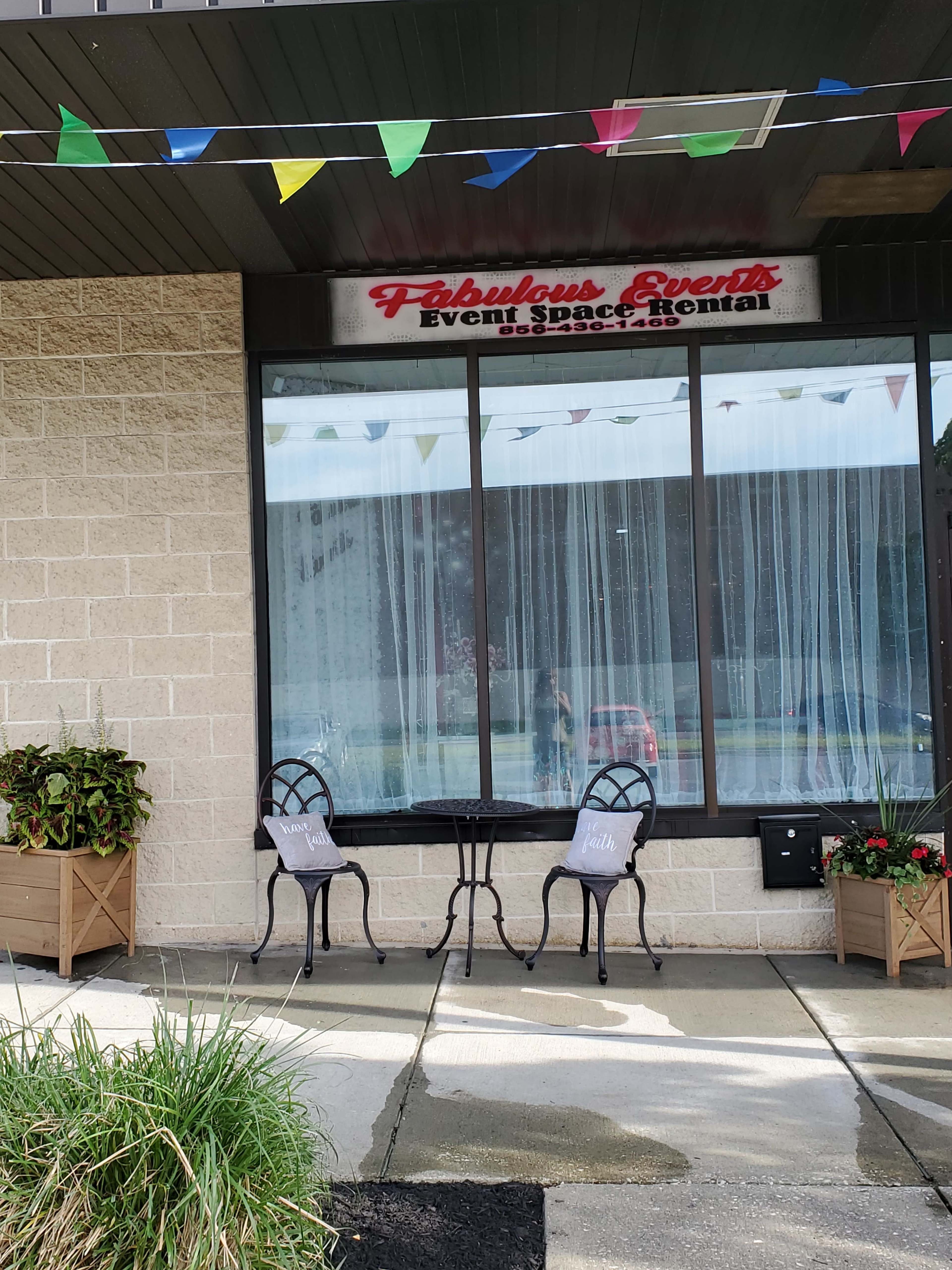 The entrance of a venue called "Fabulous Events," featuring a small table with two chairs and decorative planters on either side.