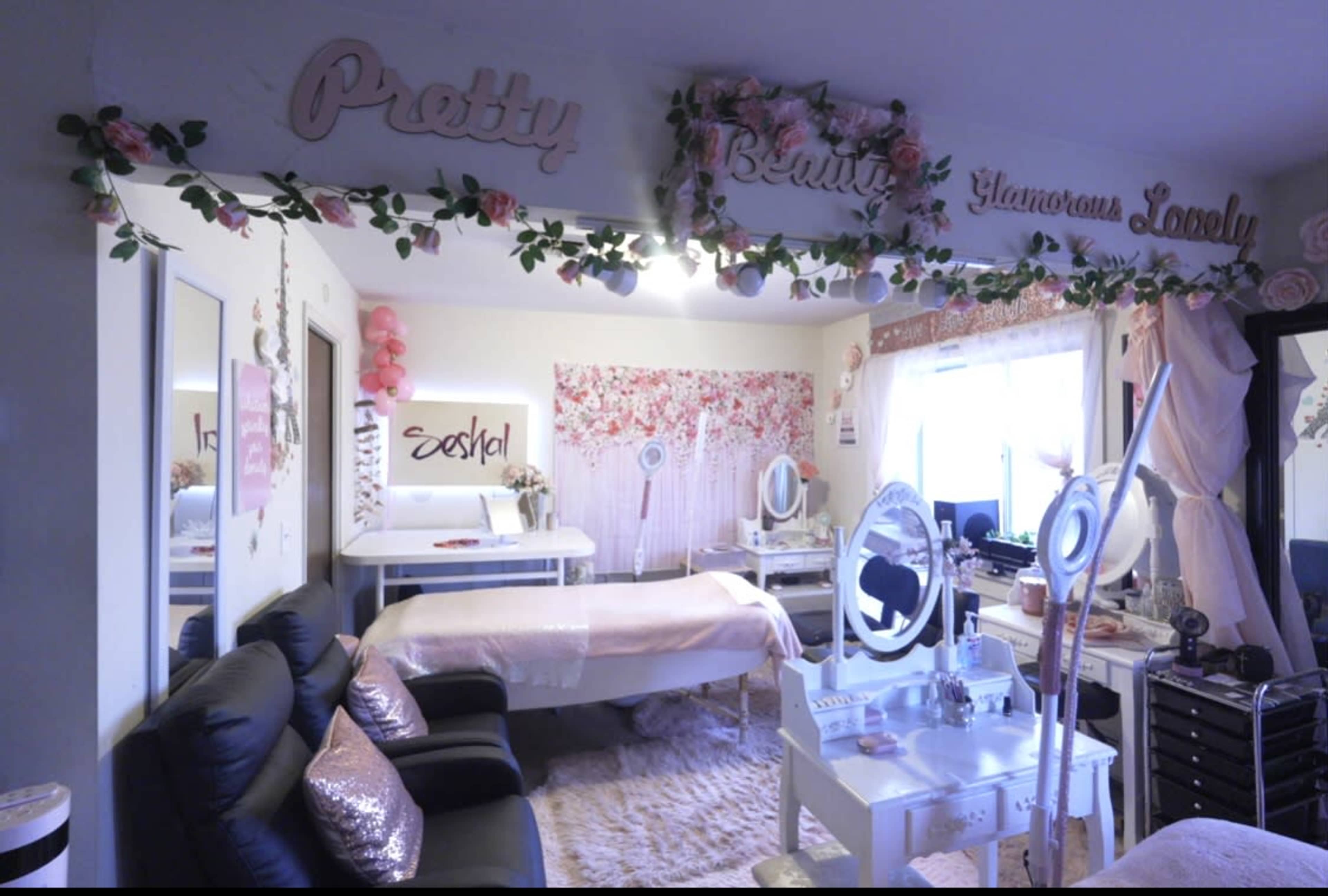 A beauty studio with pink decor, treatment beds, and mirrored tables arranged for aesthetic services.