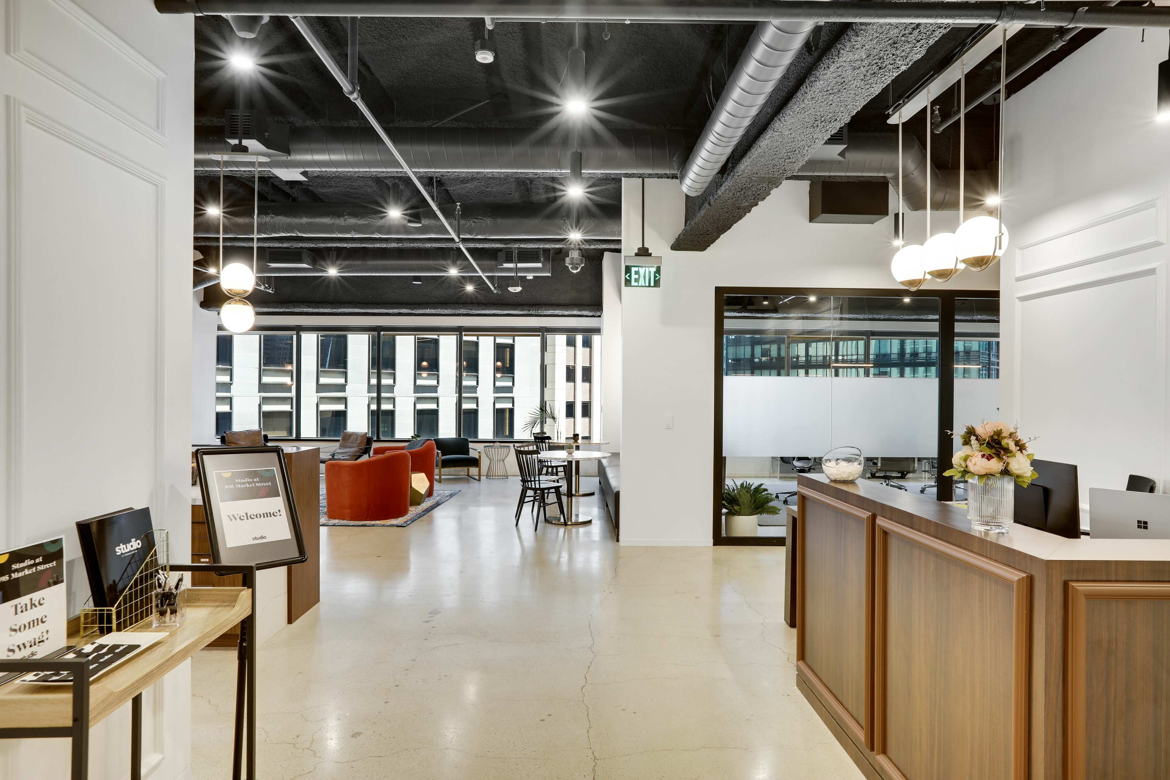 A modern office reception area with a wooden front desk, seating arrangements, and large windows revealing an urban view.