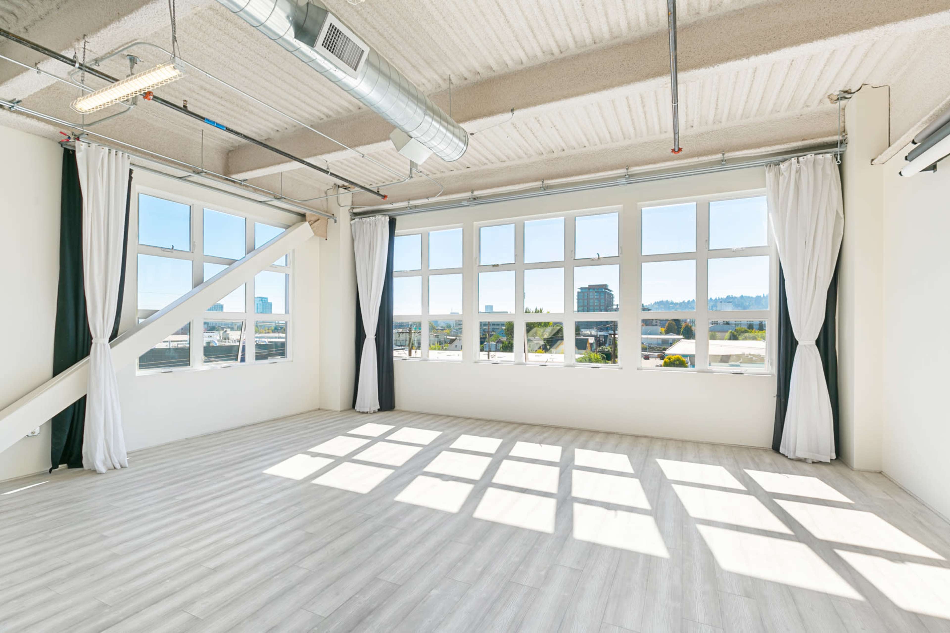 A bright, empty room with large windows and distinct shadows cast on the light-colored floor.