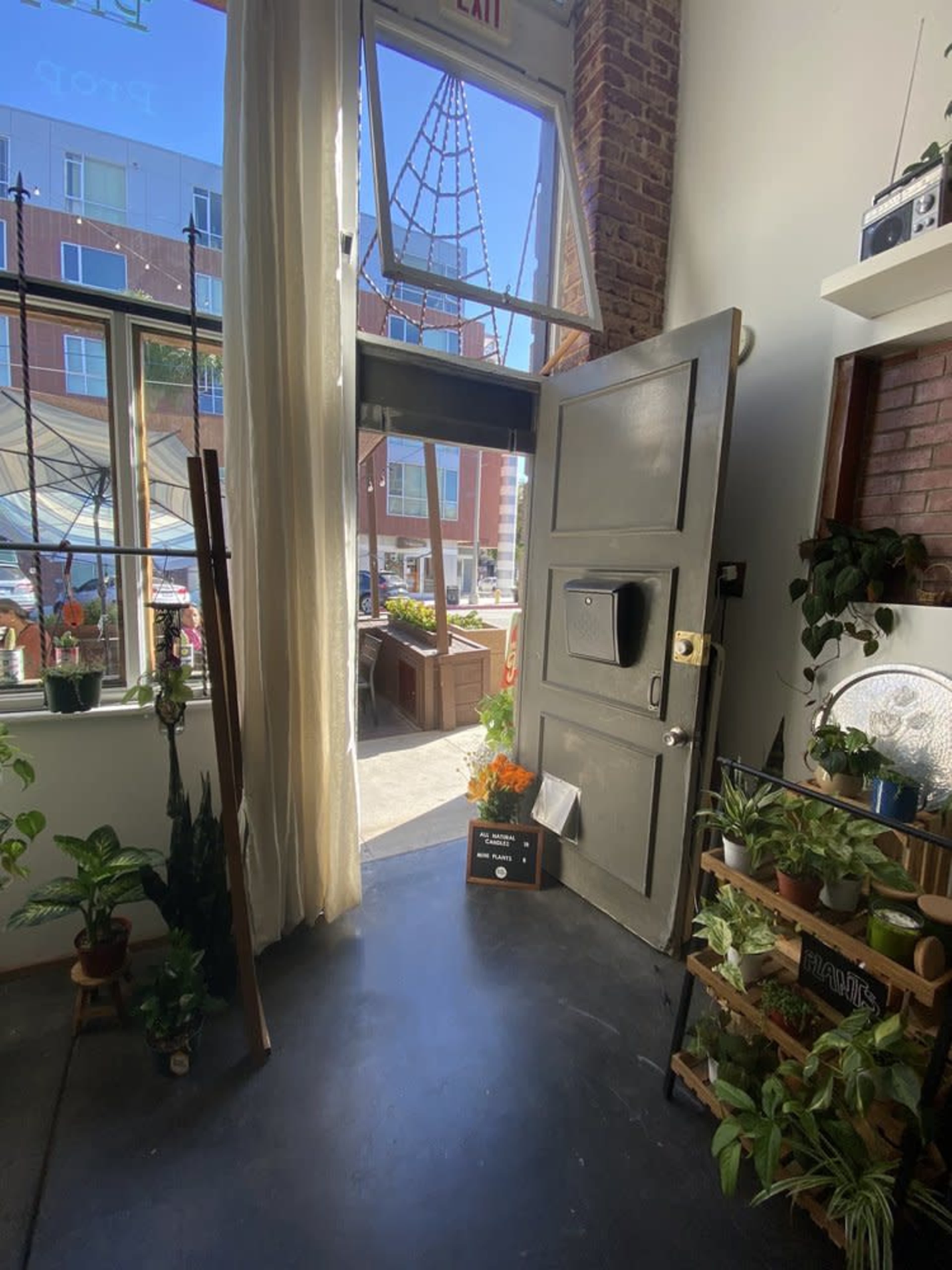 A large door stands open, revealing a view of a patio area filled with plants and a sign that reads "Welcome."