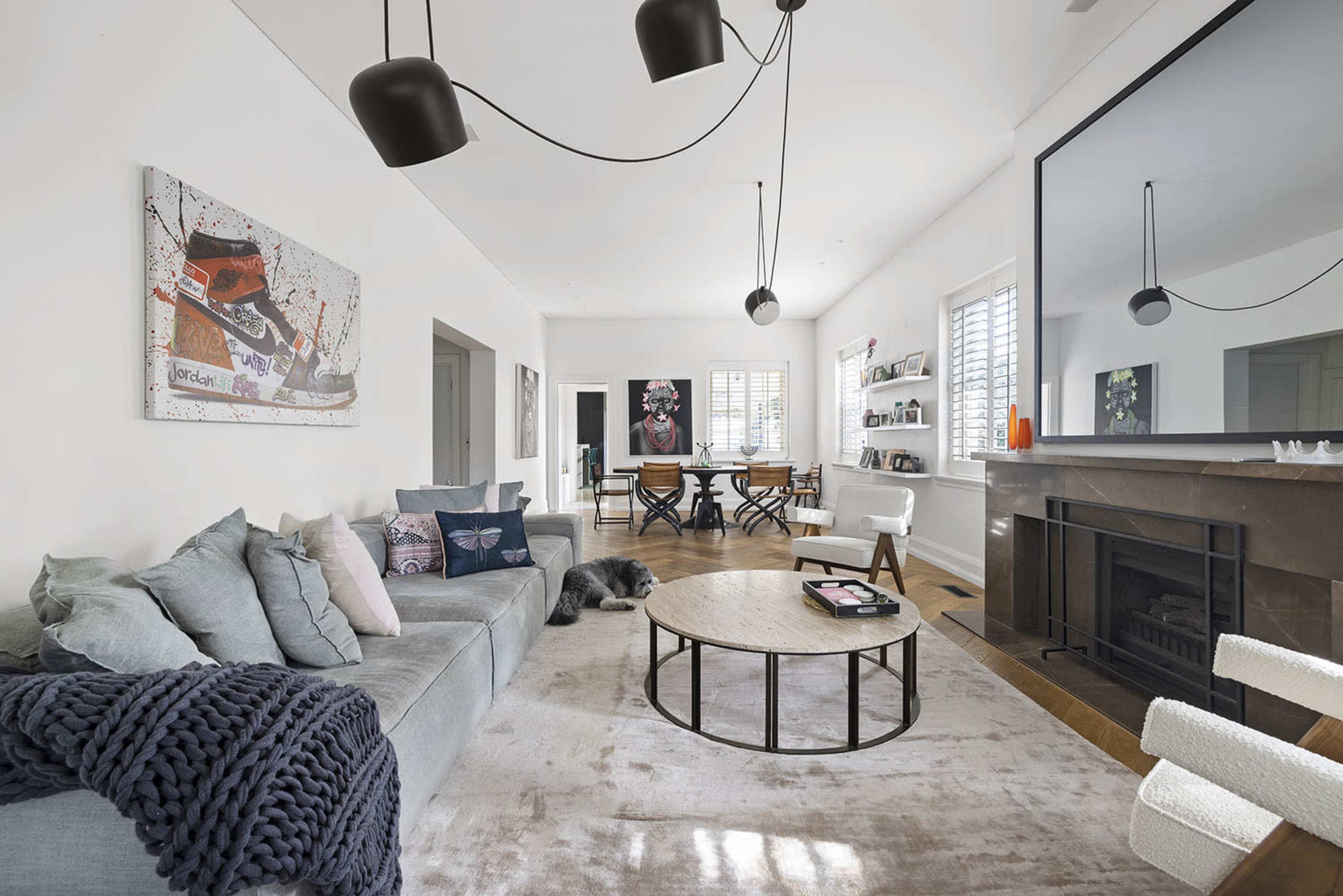 A modern living room with a gray sectional sofa, a round coffee table, and large windows that provide natural light.