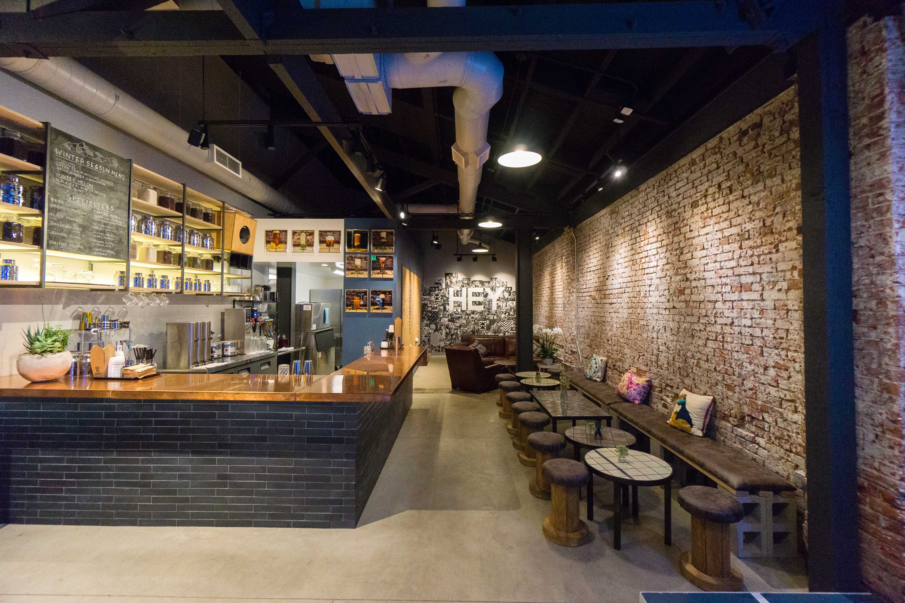 A modern café interior with a brick wall, wooden seating, a counter displaying coffee equipment, and decorative elements on the shelves.