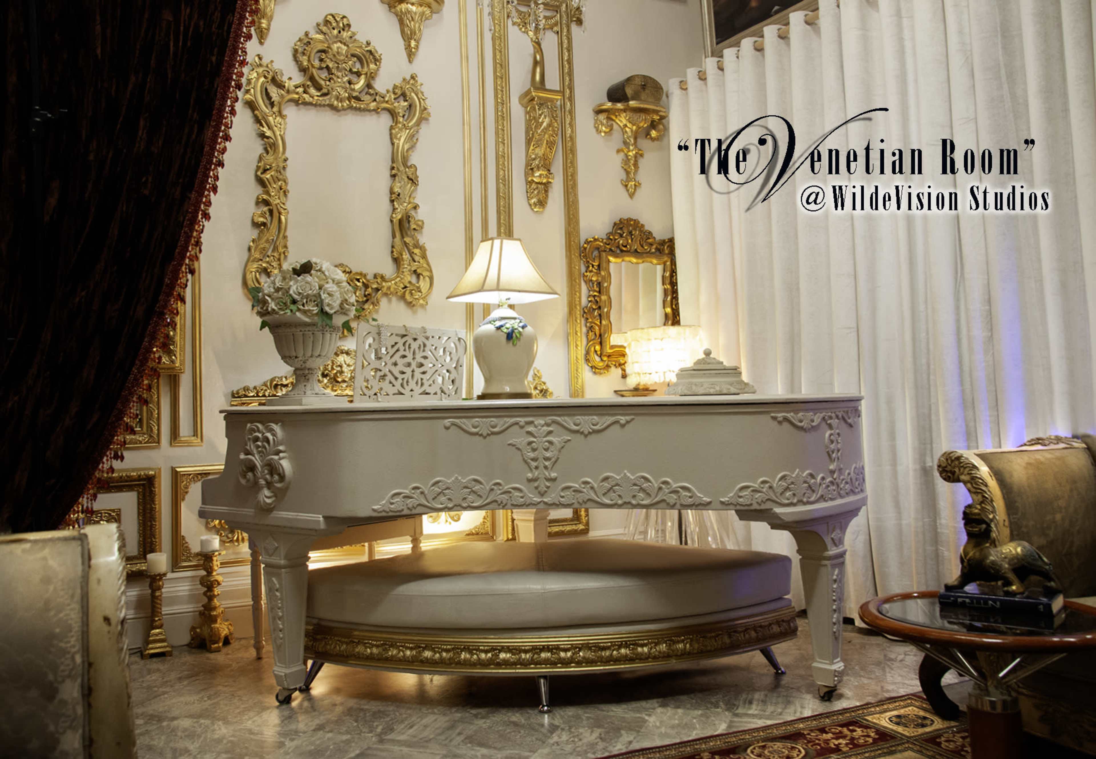 The image shows an elegant room featuring a decorative white piano, surrounded by ornate golden frames and luxurious furnishings.