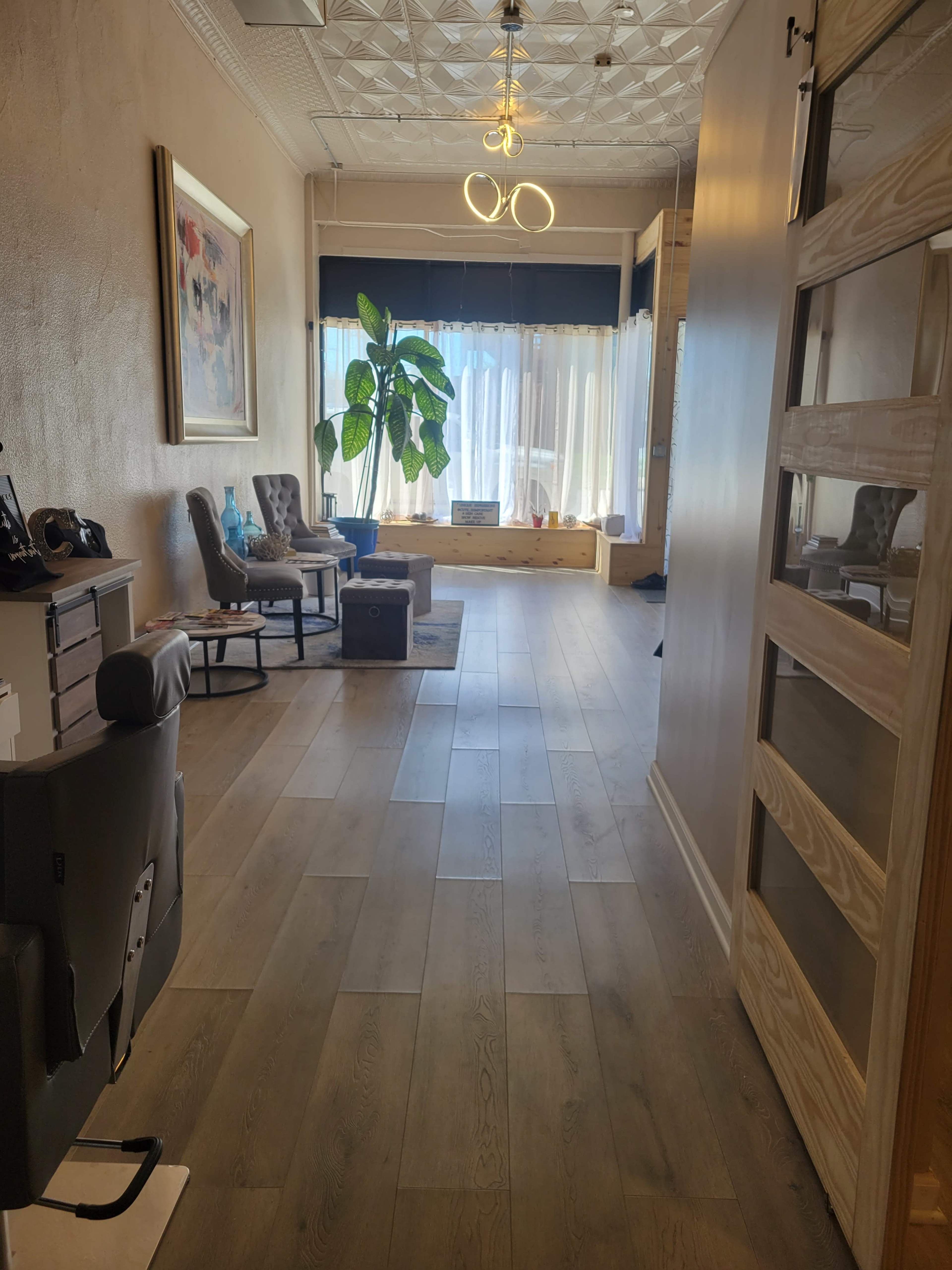 A hallway with a plant, chairs, and a window letting in natural light.