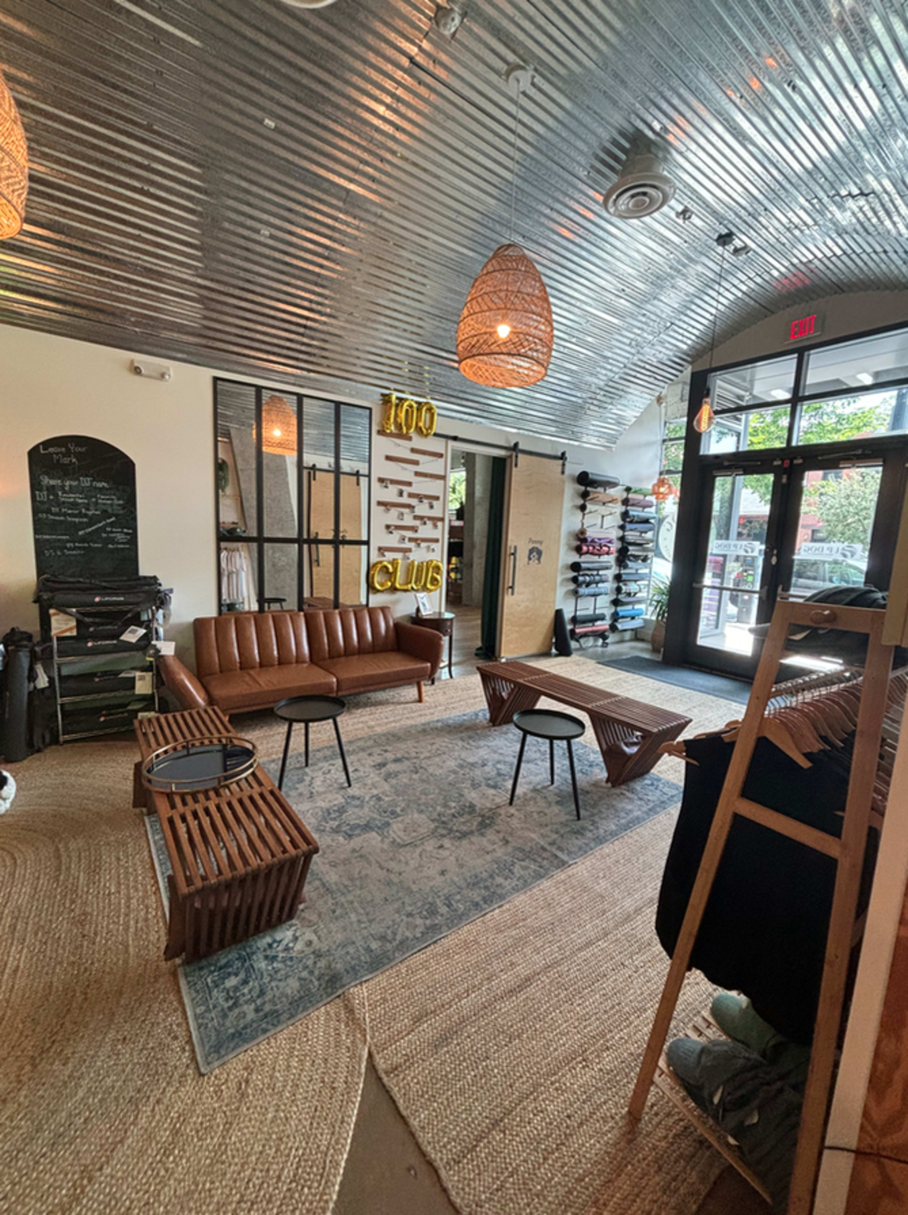 The image shows a stylish retail space featuring a leather sofa, modern decor, and large windows allowing natural light to enter.