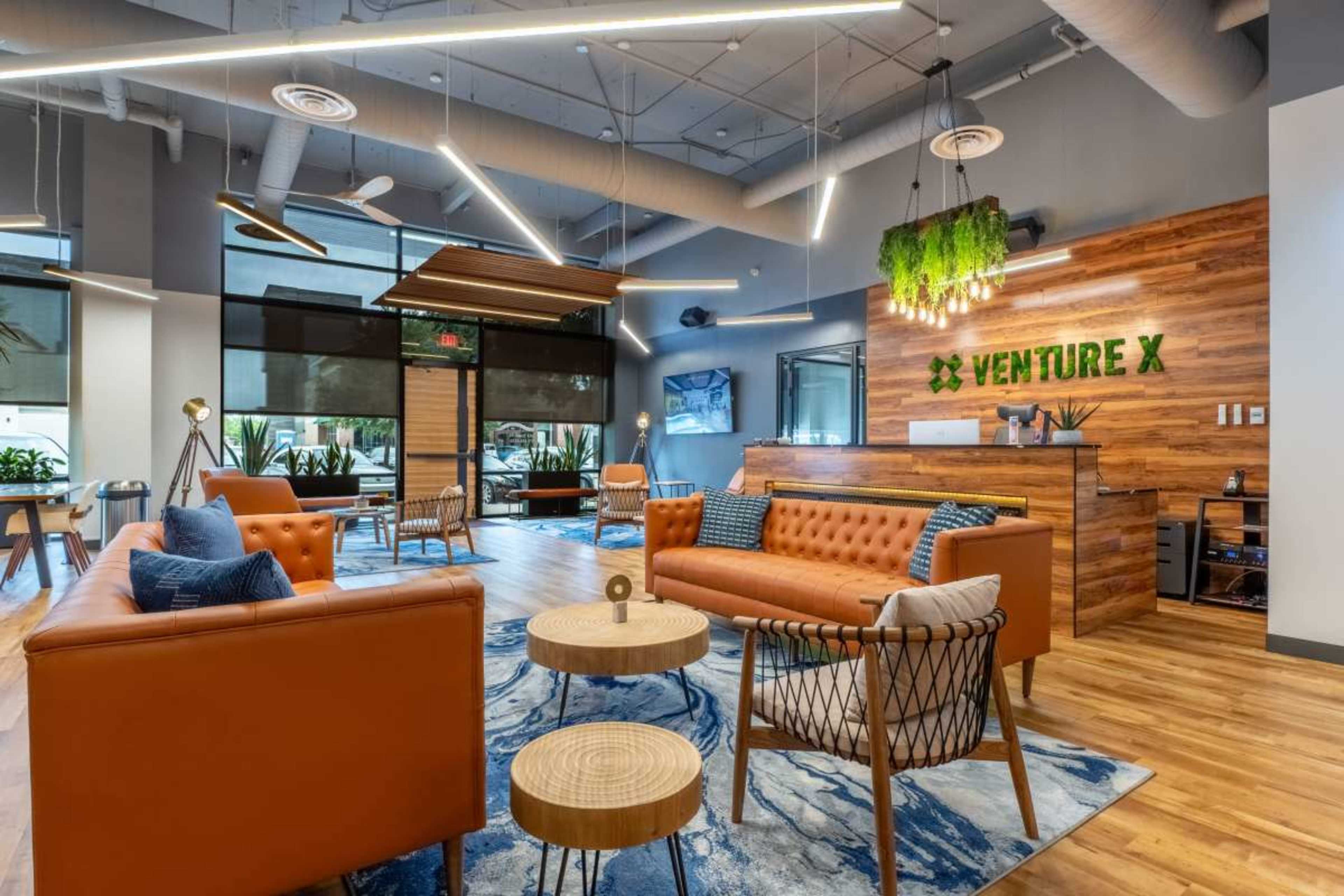 A modern office lobby with comfortable seating, wooden accents, and greenery, designed for a collaborative workspace.