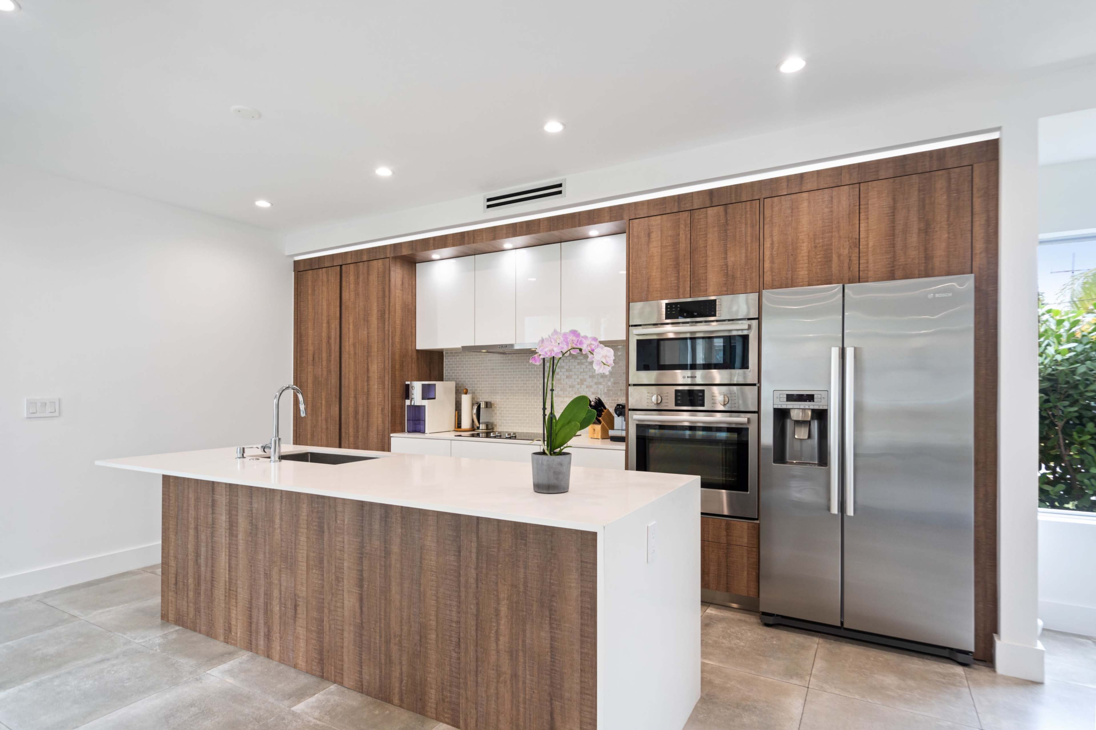 A modern kitchen featuring a large island, stainless steel appliances, and wooden cabinetry.
