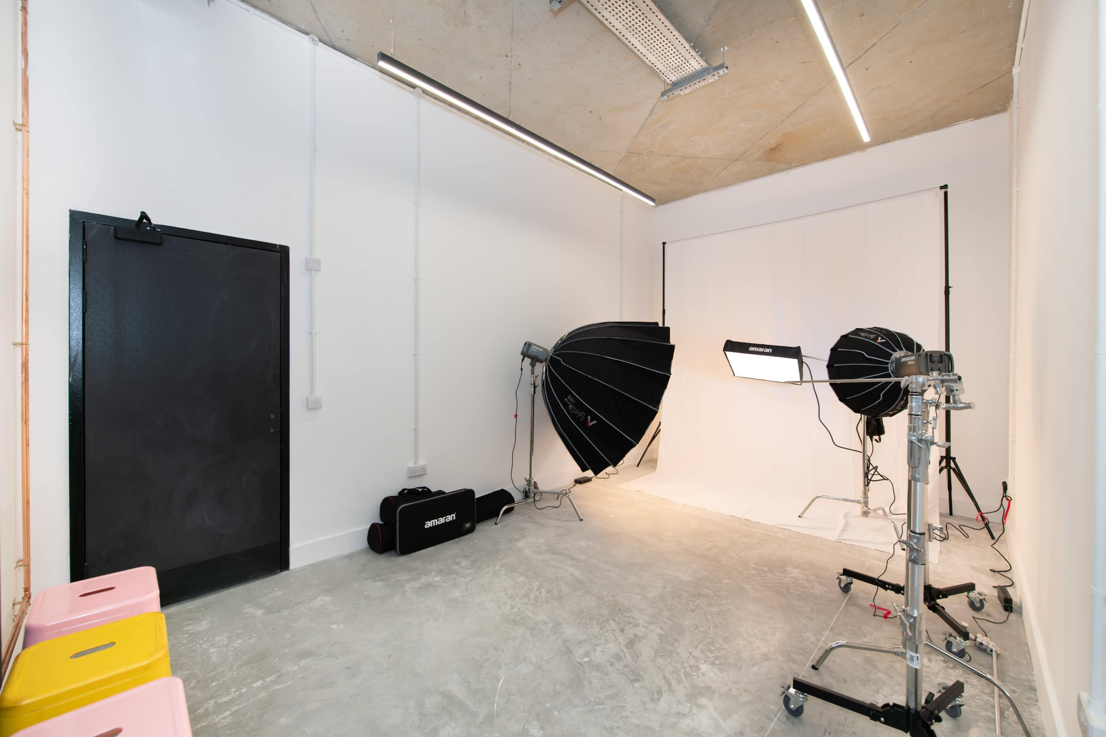 A photography studio equipped with two large softbox lights, a backdrop, and a black door.