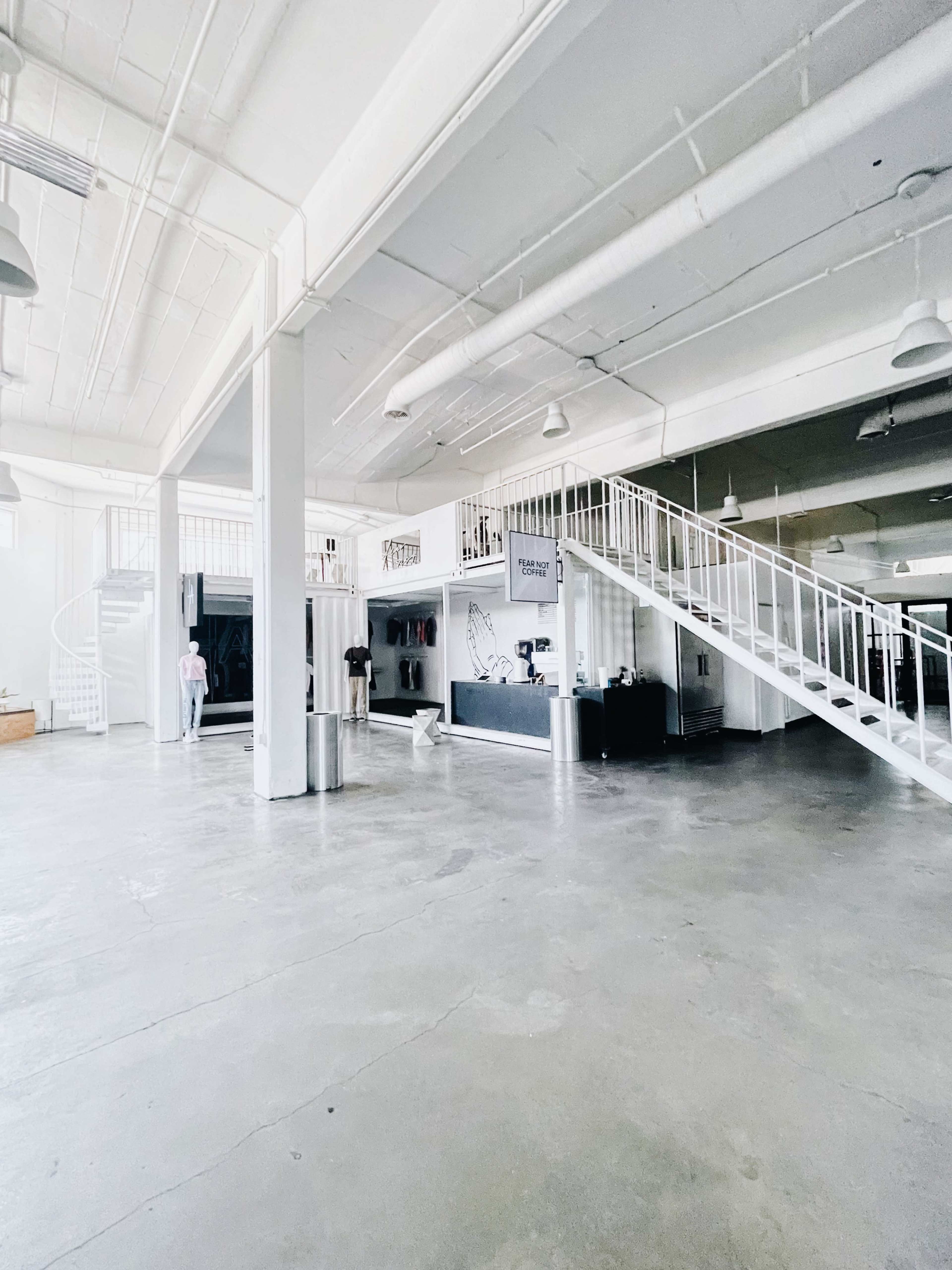 A spacious, open interior of a building featuring a reception area, a staircase, and polished concrete floors.